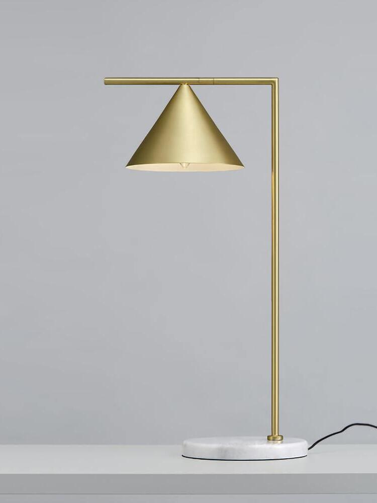 Gold-tone cone lamp with round pale base and visible power cord