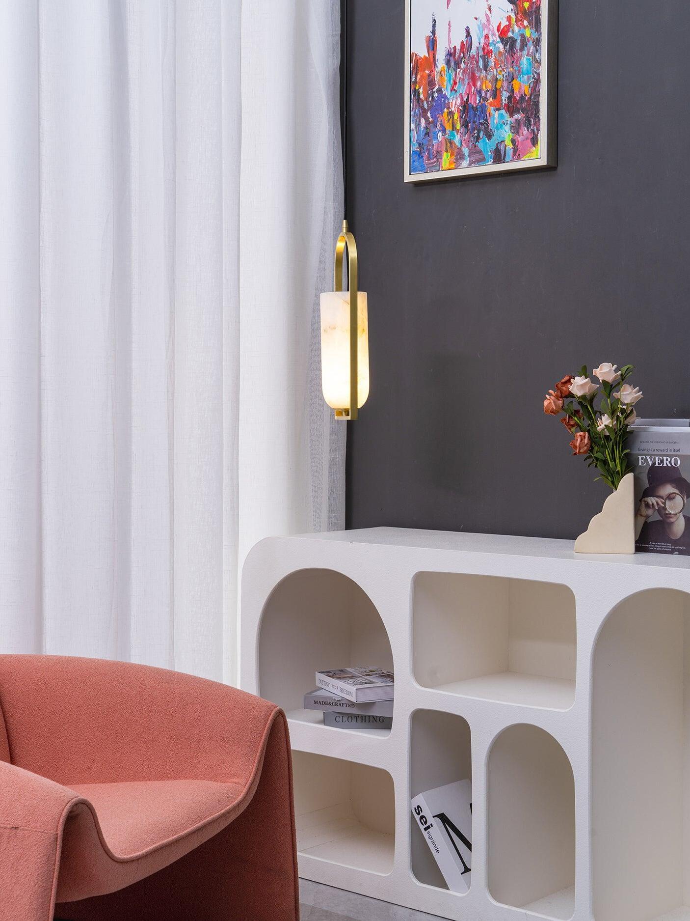 Side view of a glowing Melange pendant near curtains, a white console and a pink chair