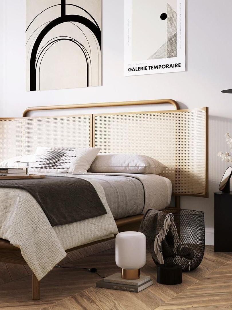 Bedroom with woven headboard, neutral bedding, arched wall art and a bedside table lamp
