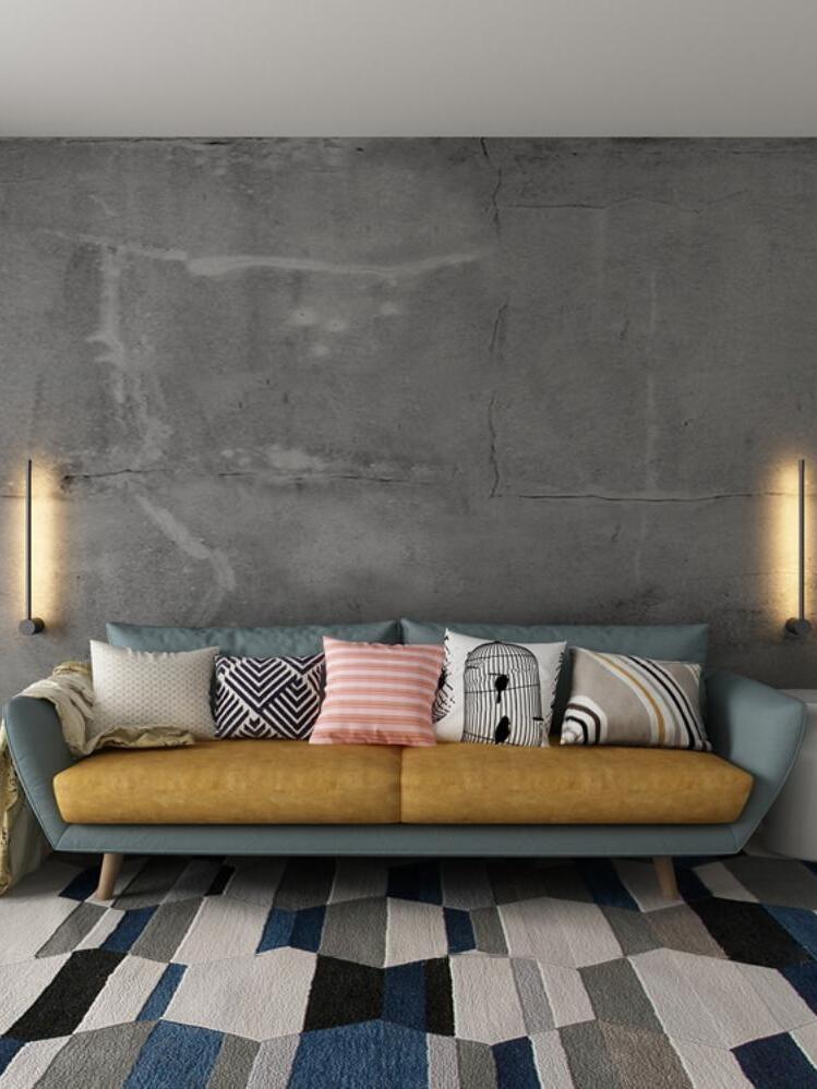Tall linear wall lights beside a long sofa
