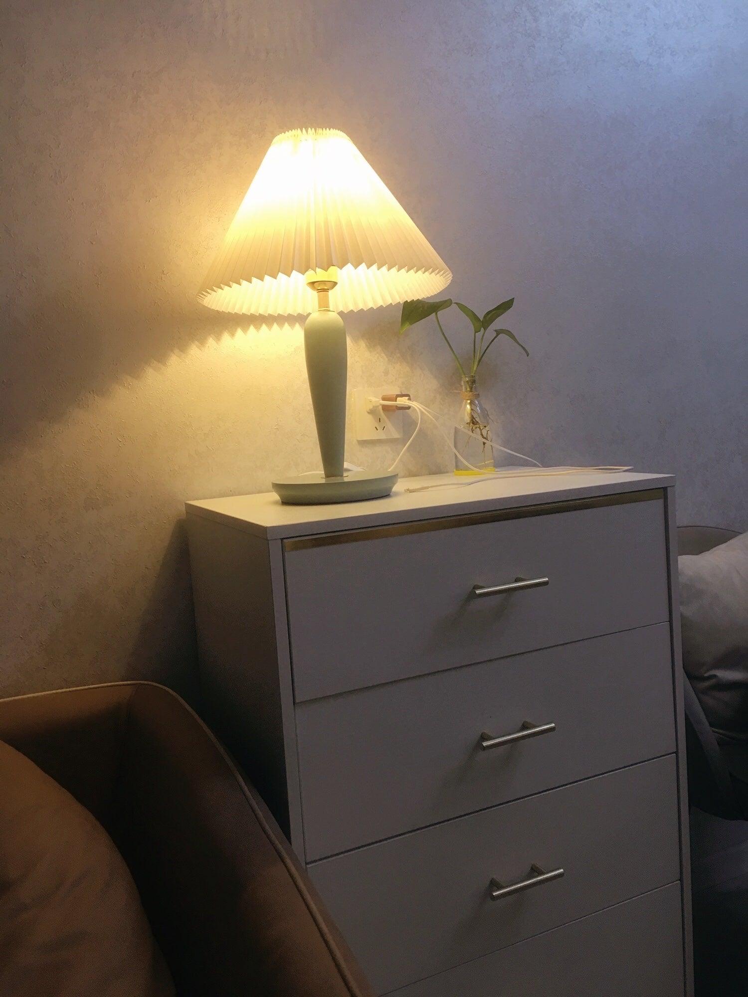 Light-blue lamp glowing on bedroom chest