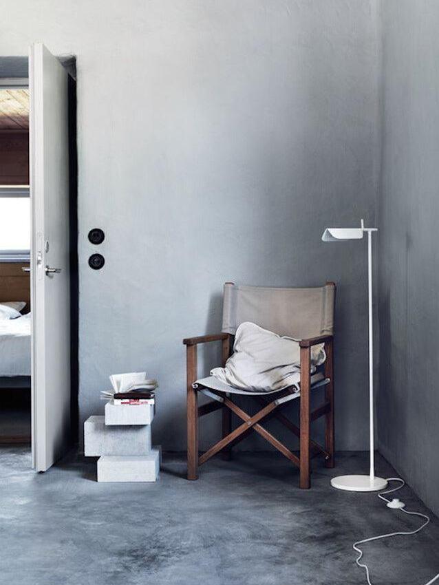 White floor lamp beside a folding chair