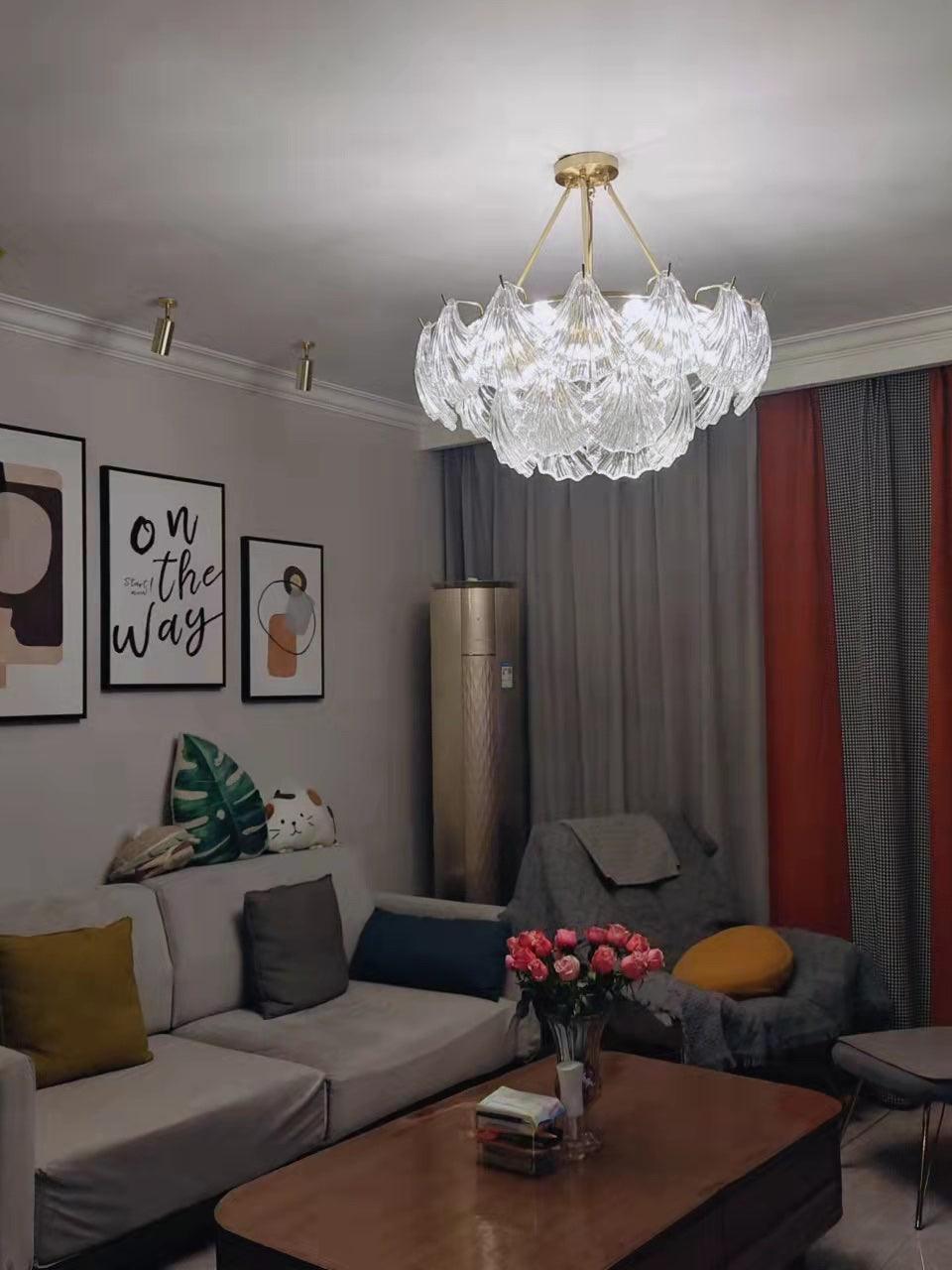 Round shell-panel ceiling light above a gray sofa with red curtains and framed posters