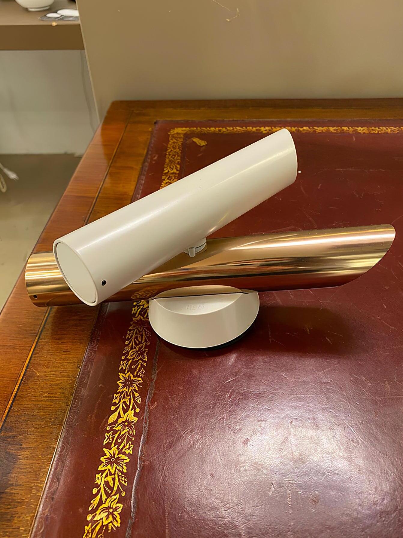 White and rose-gold lamp resting on wood surface