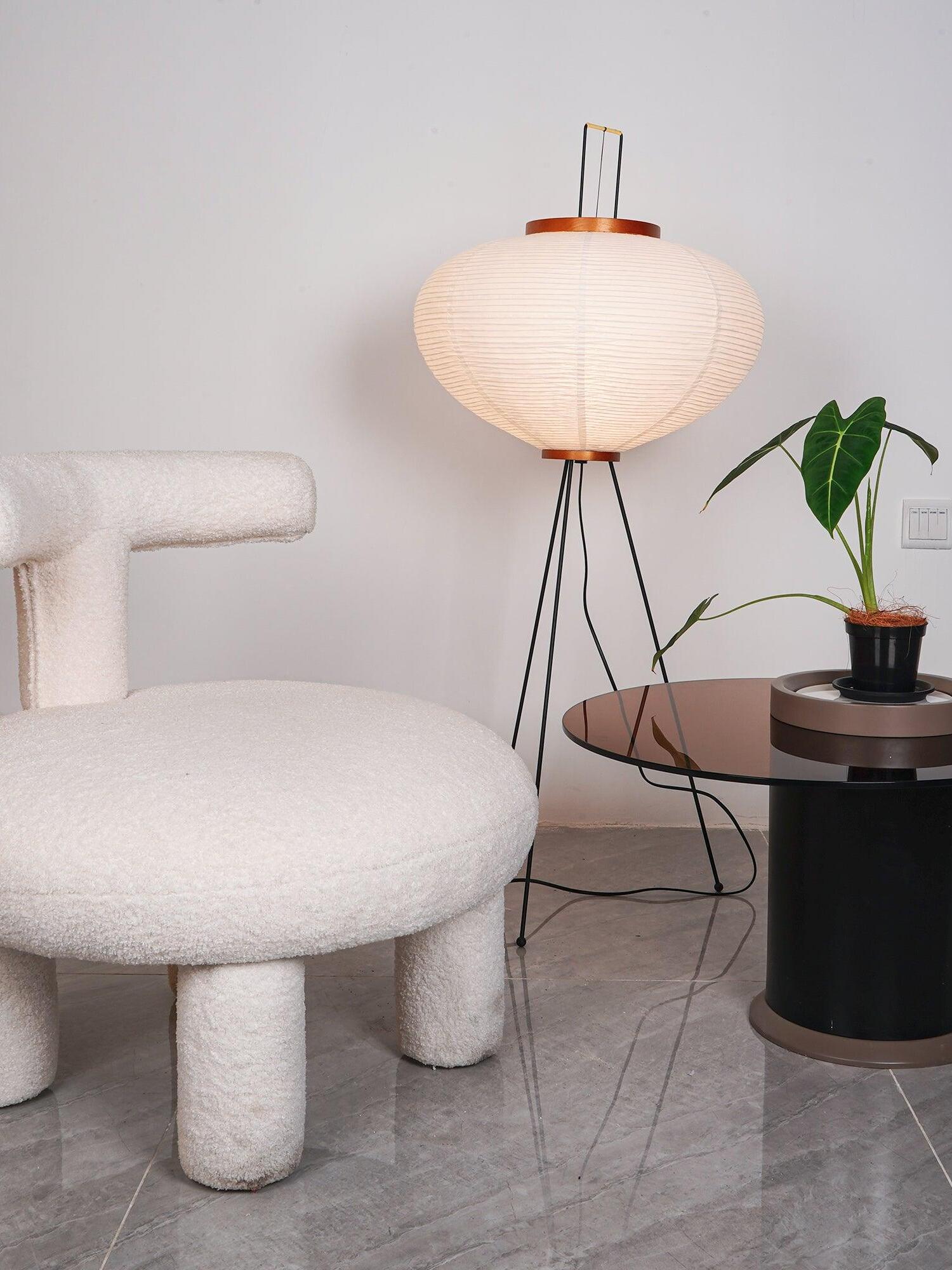 Lit rounded paper lamp beside pale chair