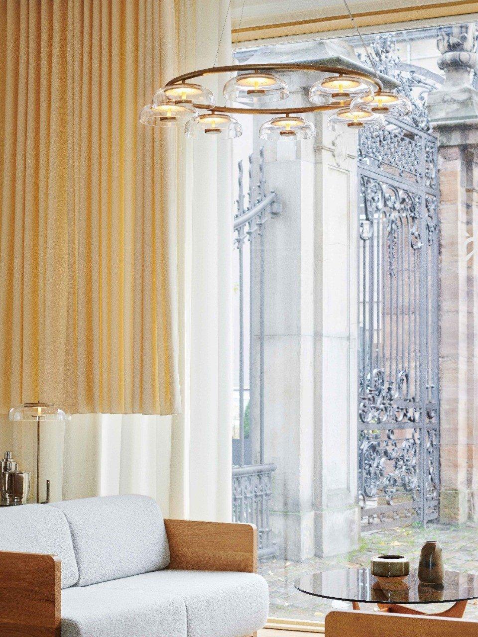 Blossi chandelier in a living room with a sofa and tall curtains