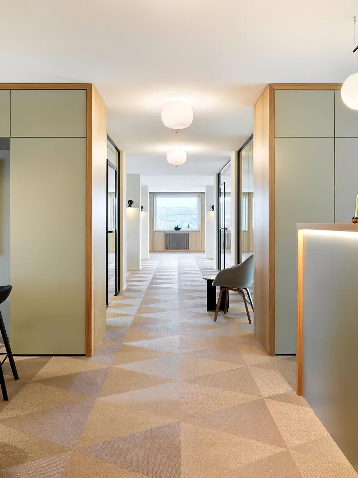 White rounded ceiling lights spaced along a corridor with cabinets and patterned flooring