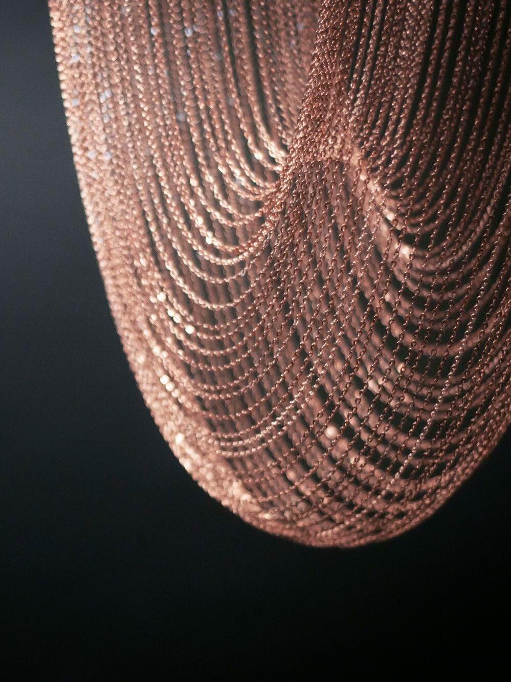 Layered rose-gold chain curves viewed close up