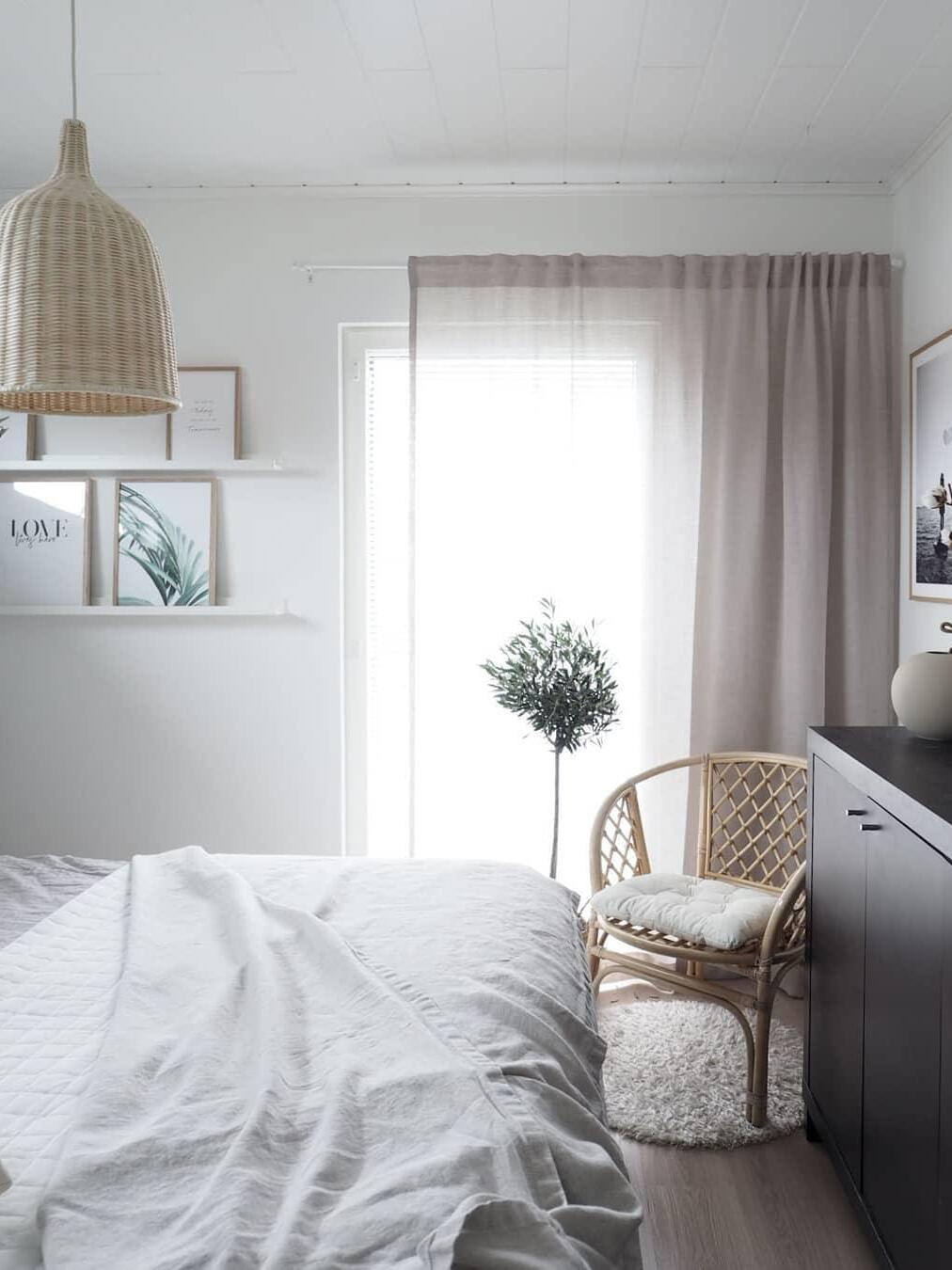 Rattan pendant beside a bed and curtained window