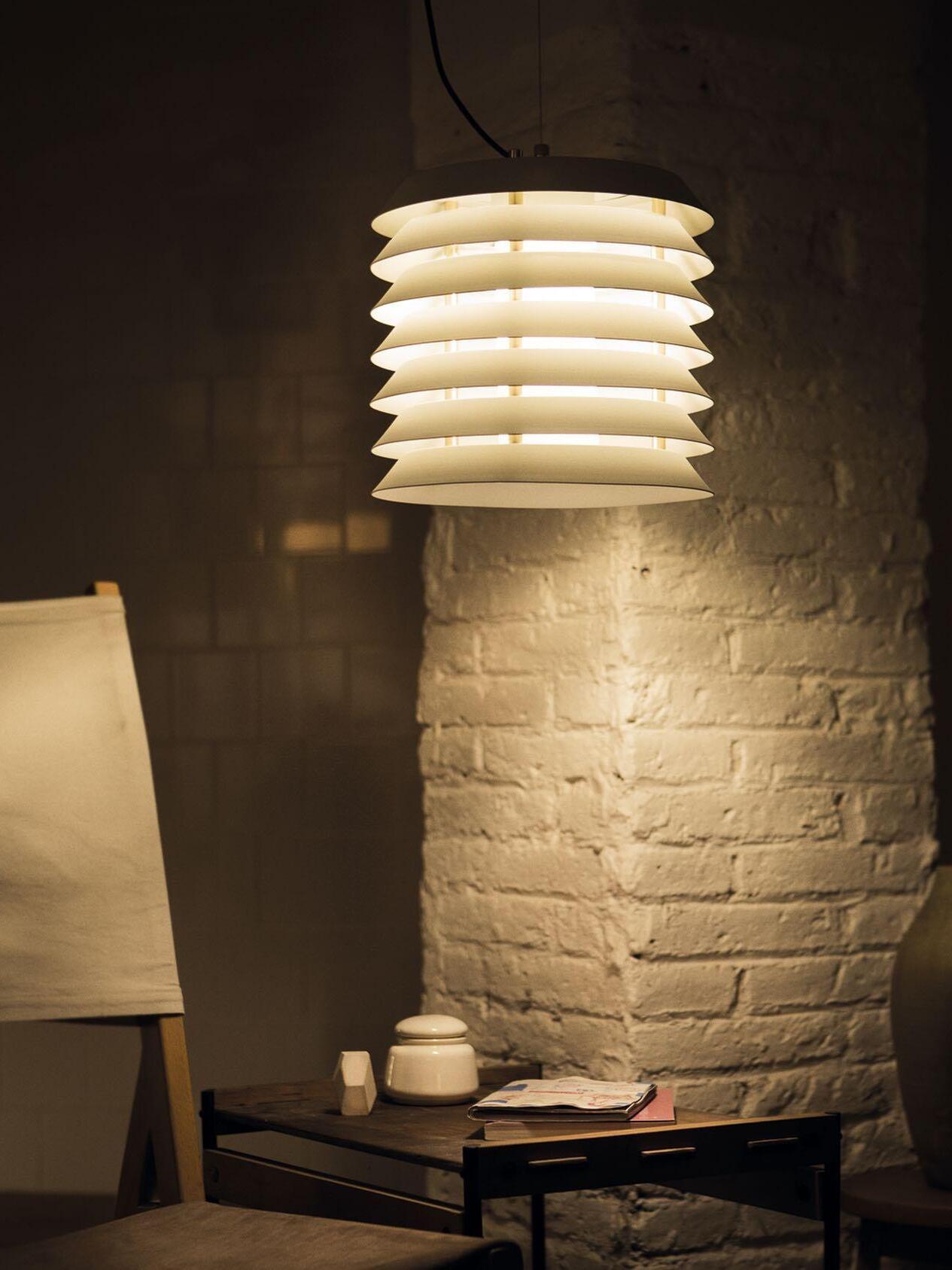 Closer view of lit layered pendant beside pale brick column and seating