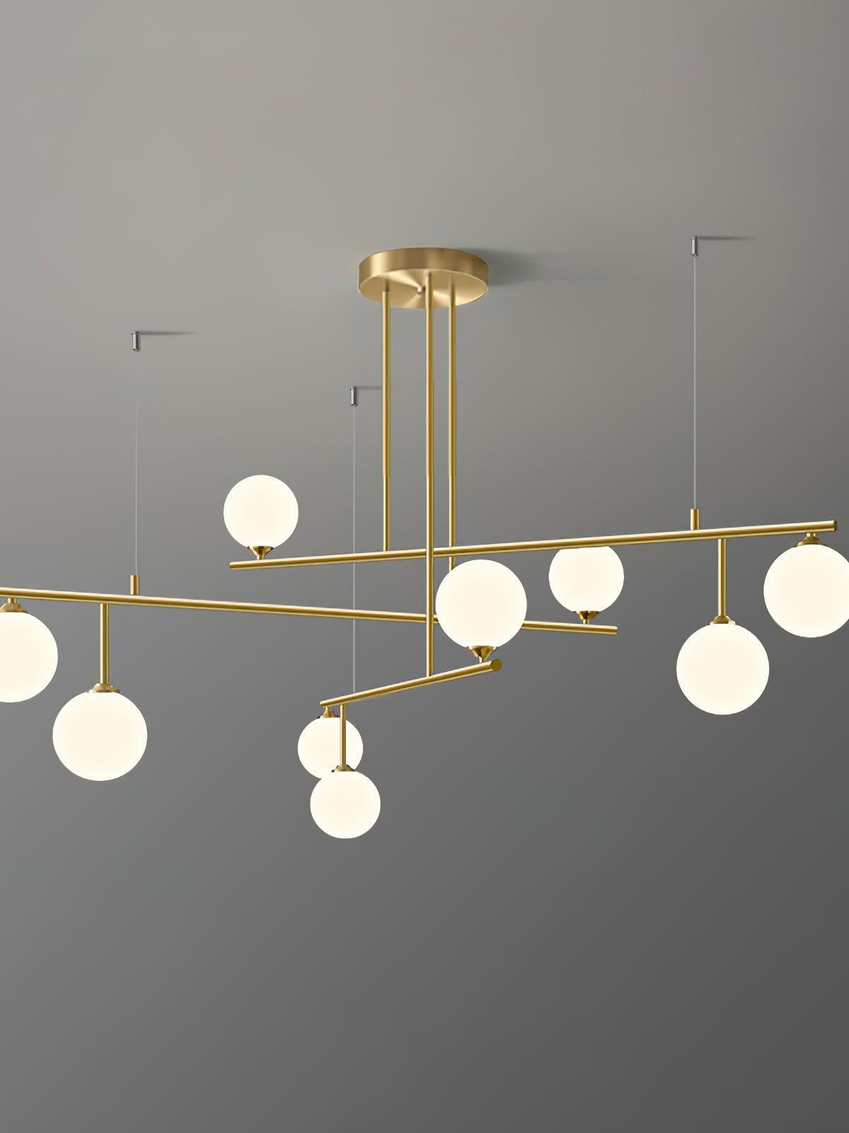 Illuminated white globes above and below the Arteriors chandelier’s tiered brass-tone frame