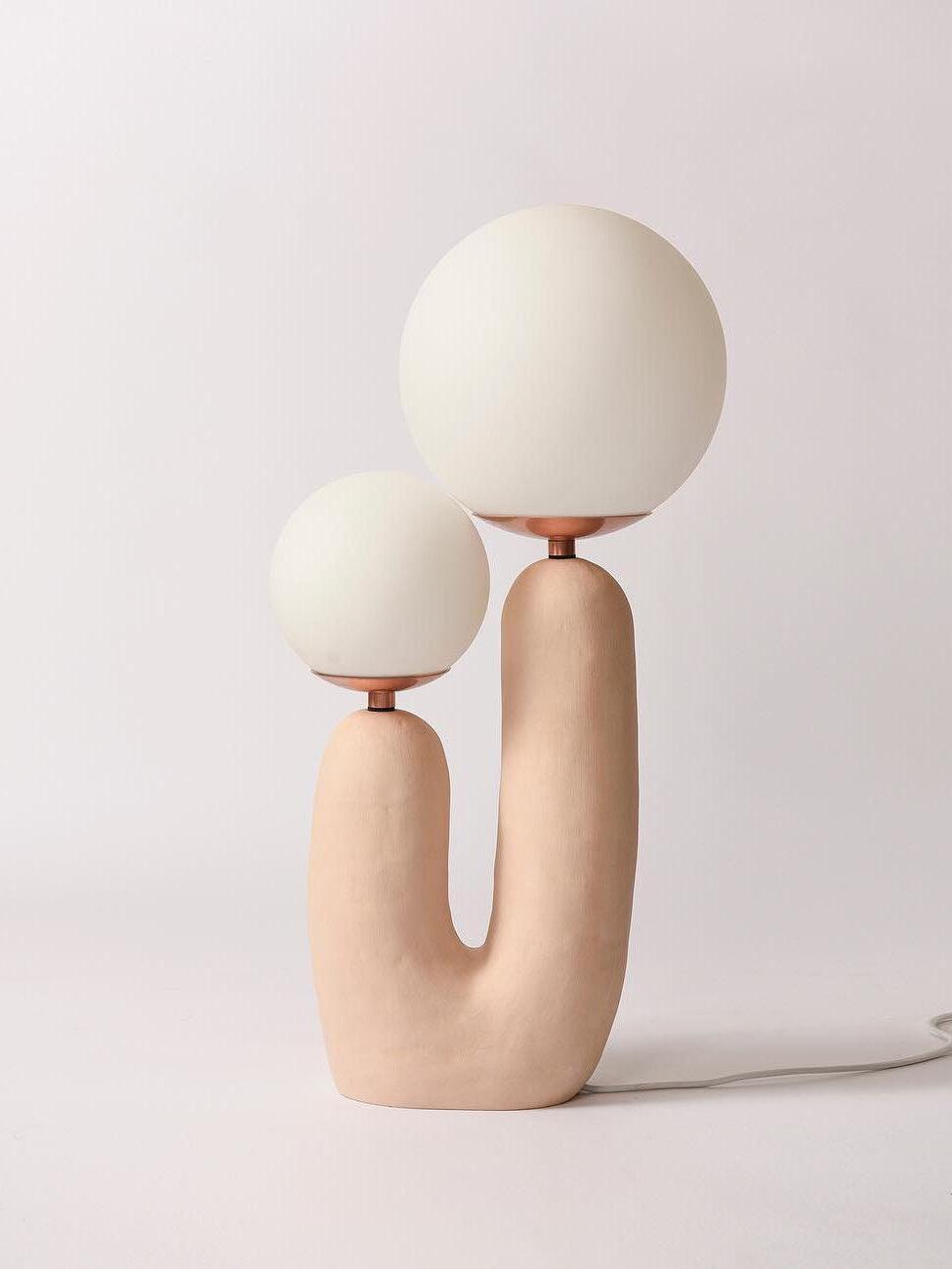 Pale pink Oo Rough lamp on a light background, smaller left and larger right globe above a textured U-shaped body