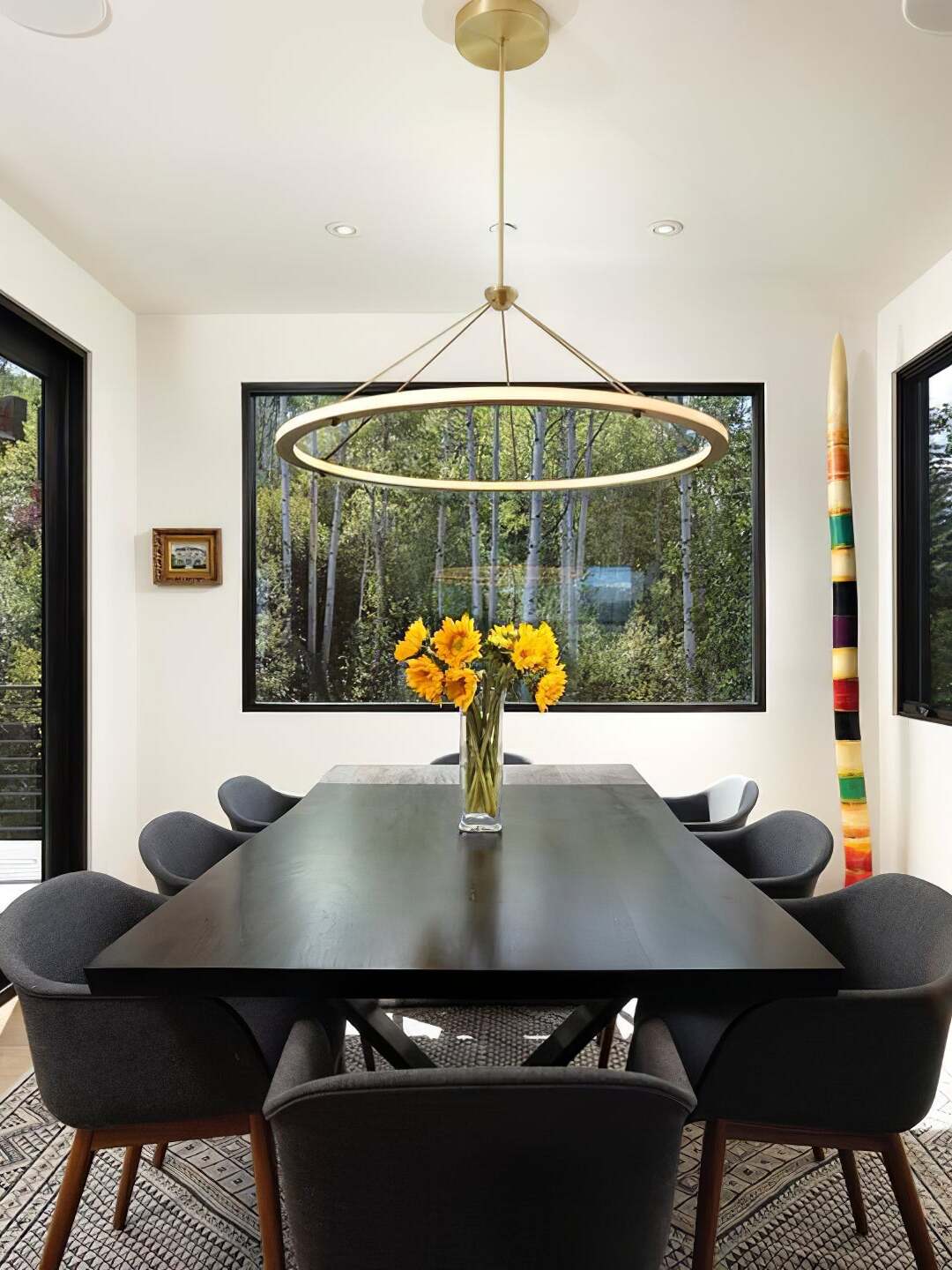 Gold single ring pendant above dark dining table and flowers