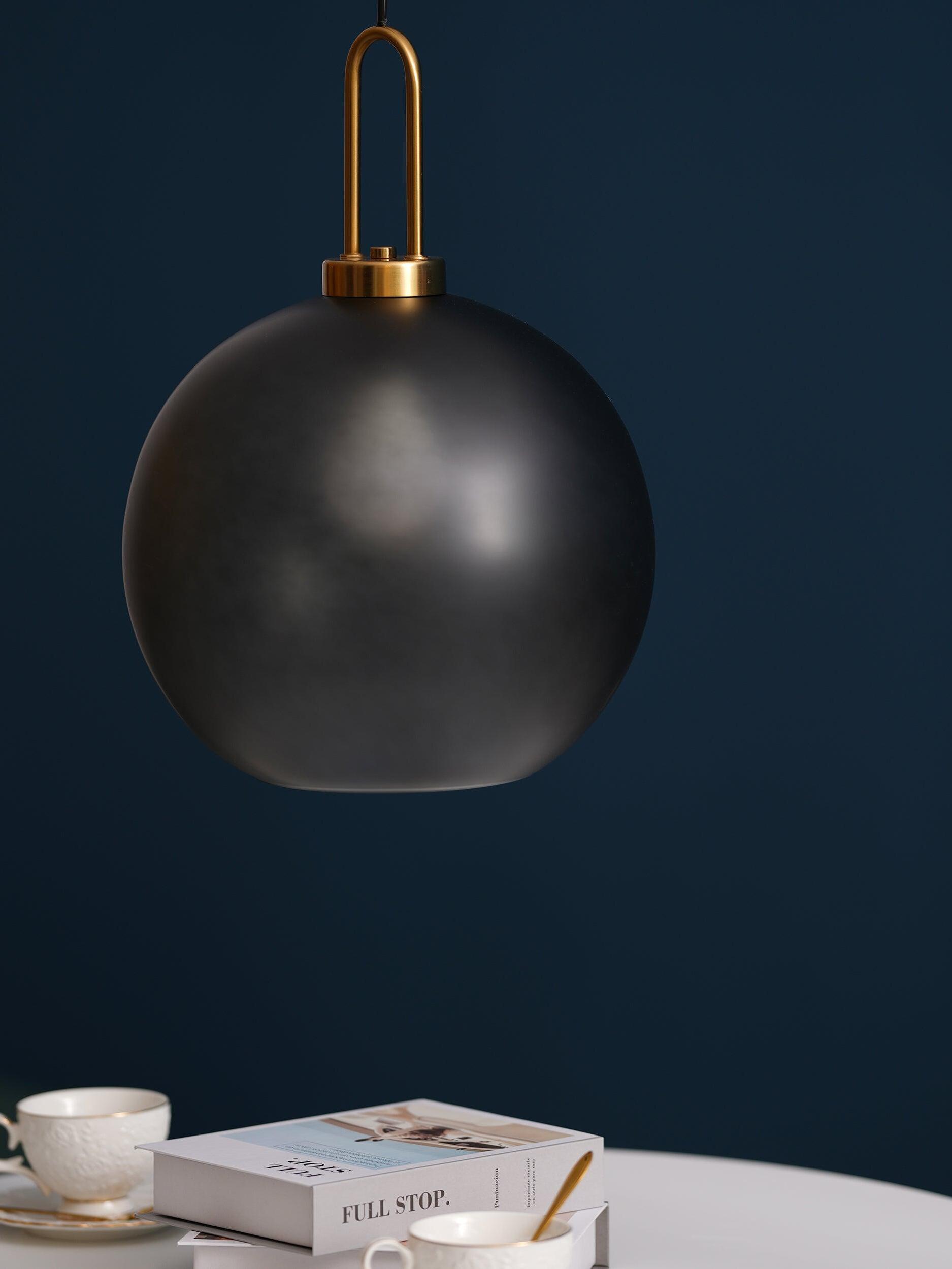 Dark rounded glass pendant above cups and books