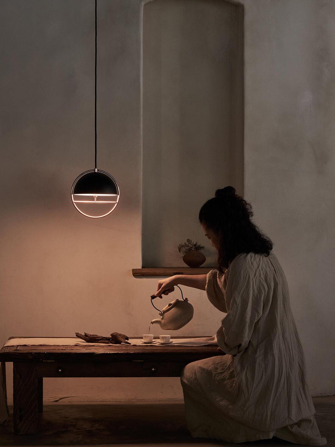 Small illuminated ring pendant above wood table