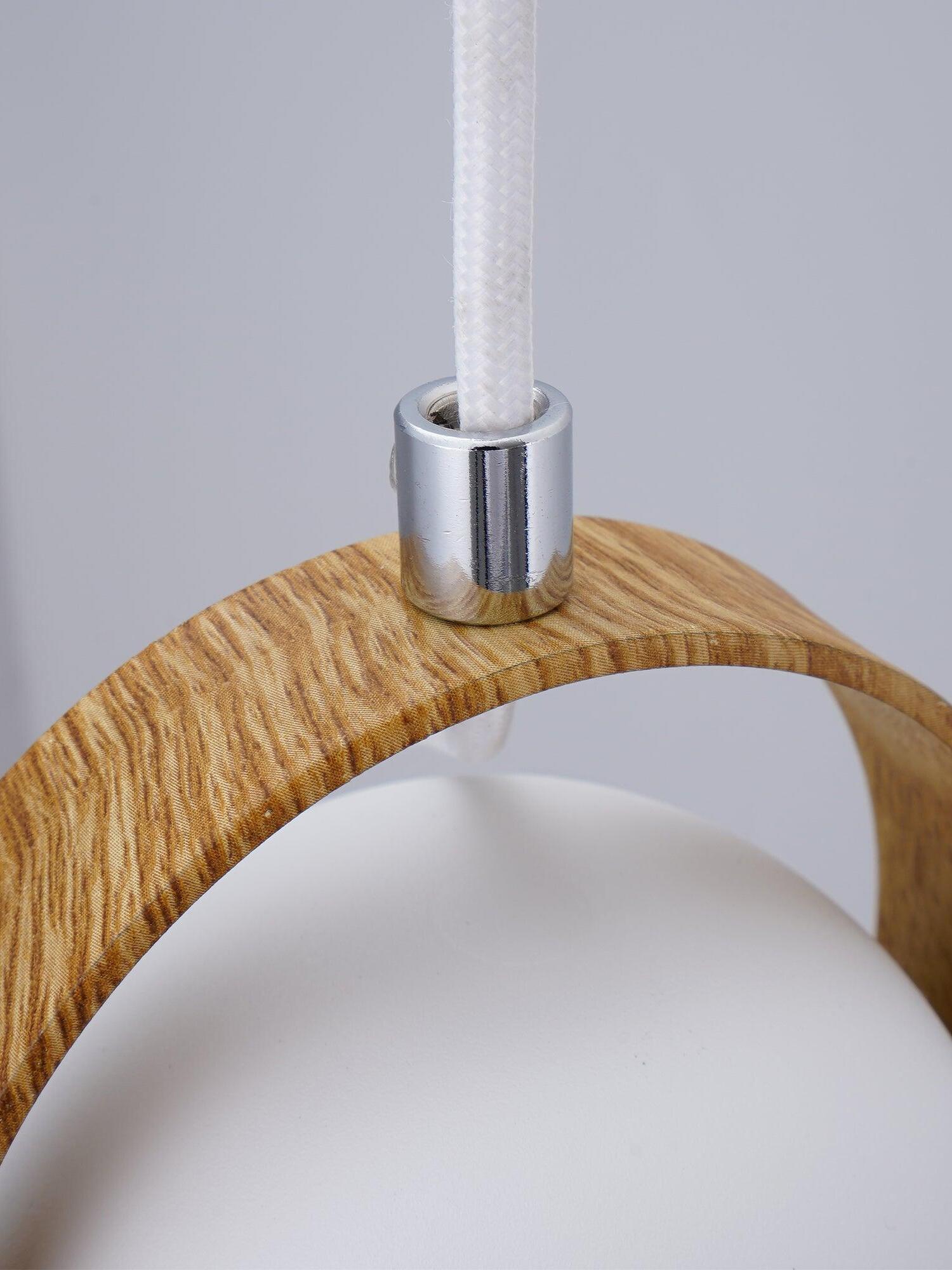 Detail of white suspension cable entering a silver-tone sleeve above the curved light wood bracket