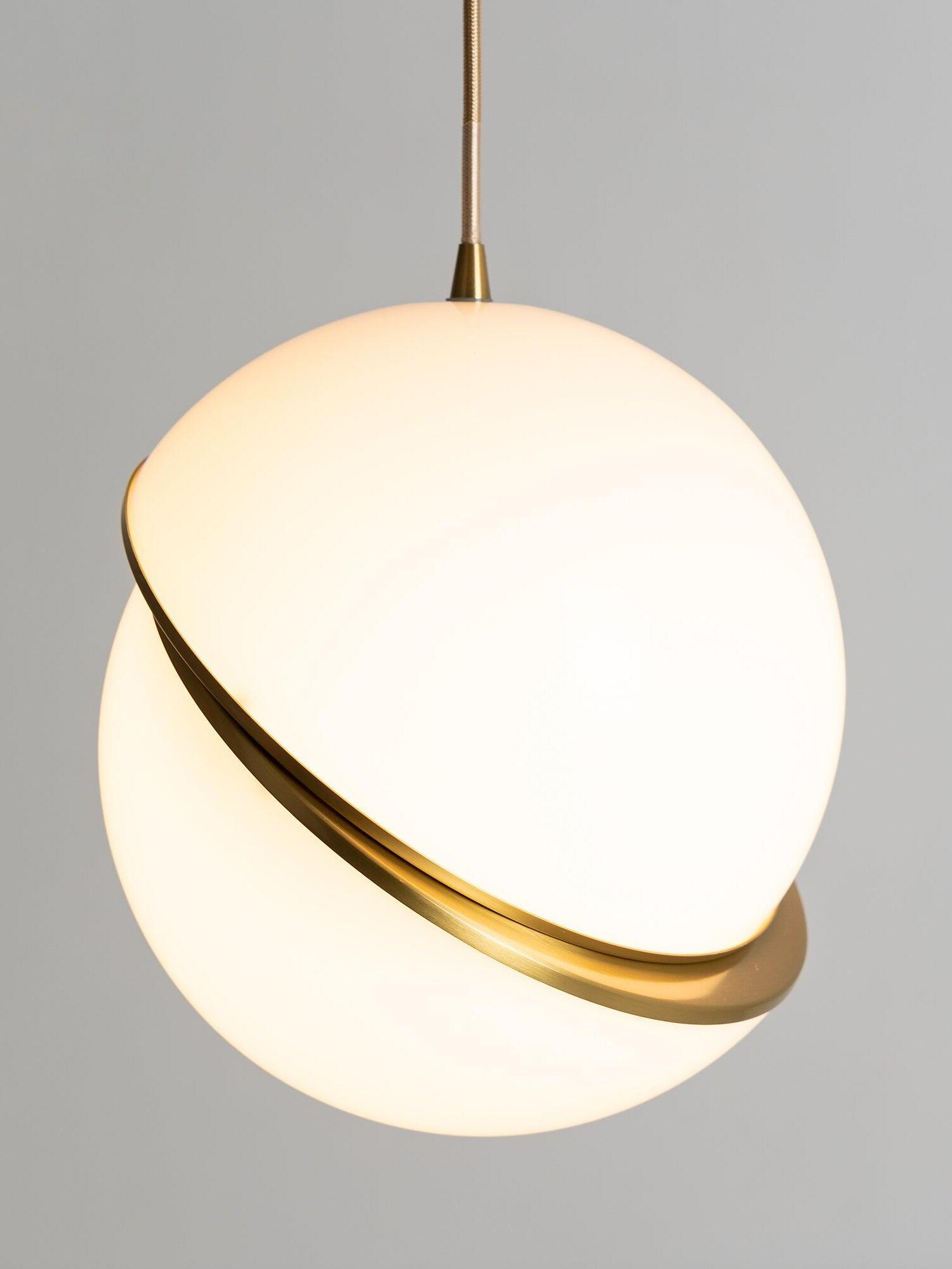 Lit close view of Crescent offset white globe halves, curved gold-colour band and textured cord against grey