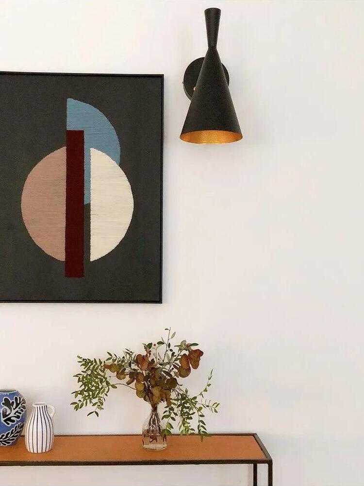 Black cone wall light above a console and framed wall art