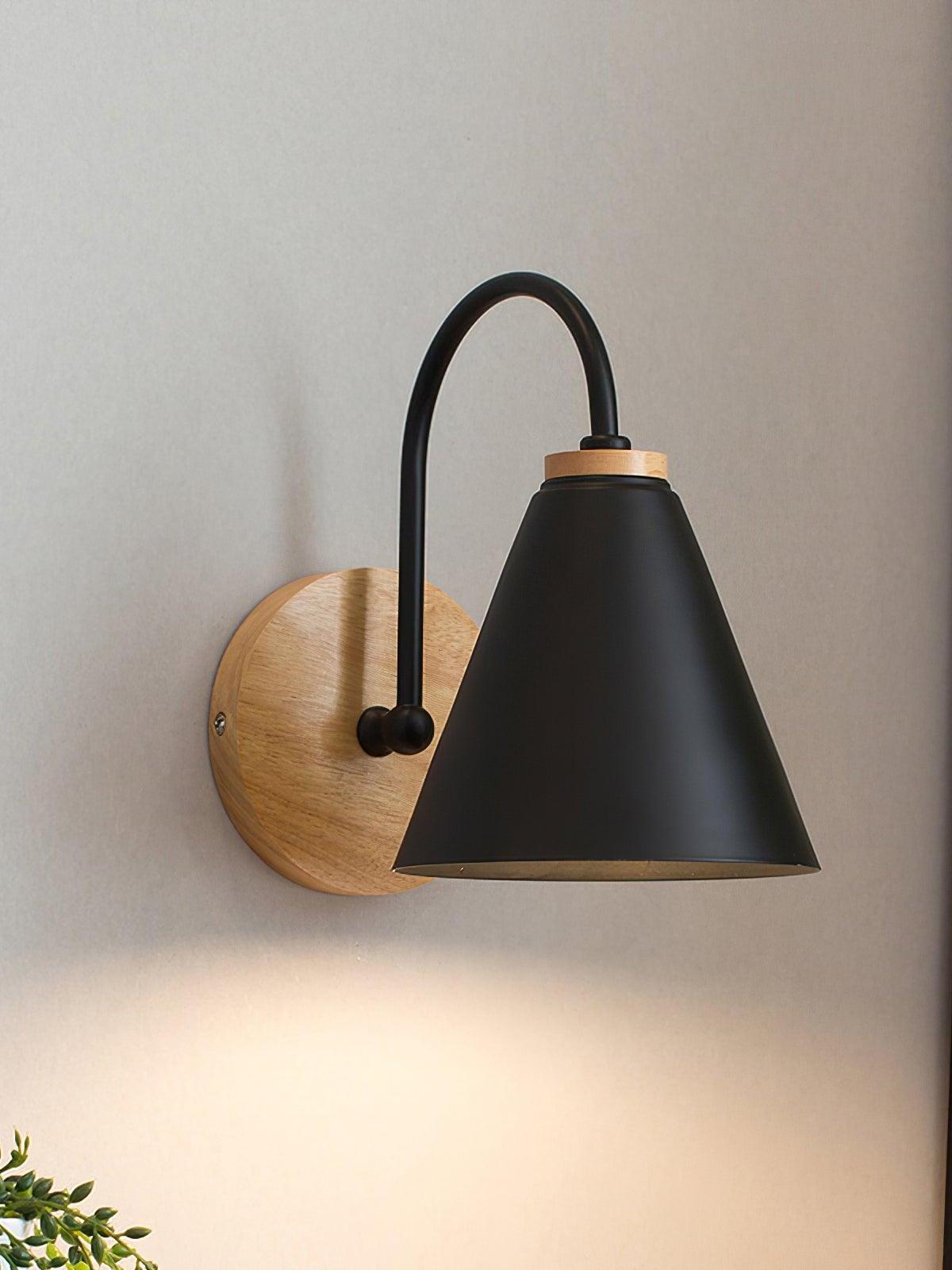 Black cone wall lamp glowing down onto a pale wall