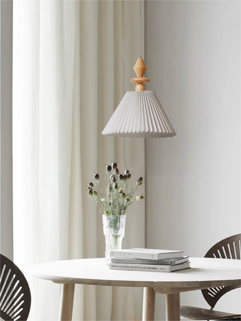 White pleated Takumi shade below a pointed wood finial over a dining table