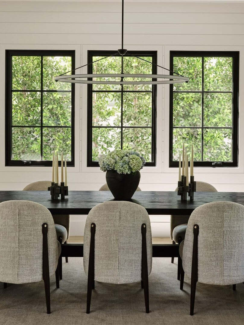 Black ring pendant above dining table by three windows