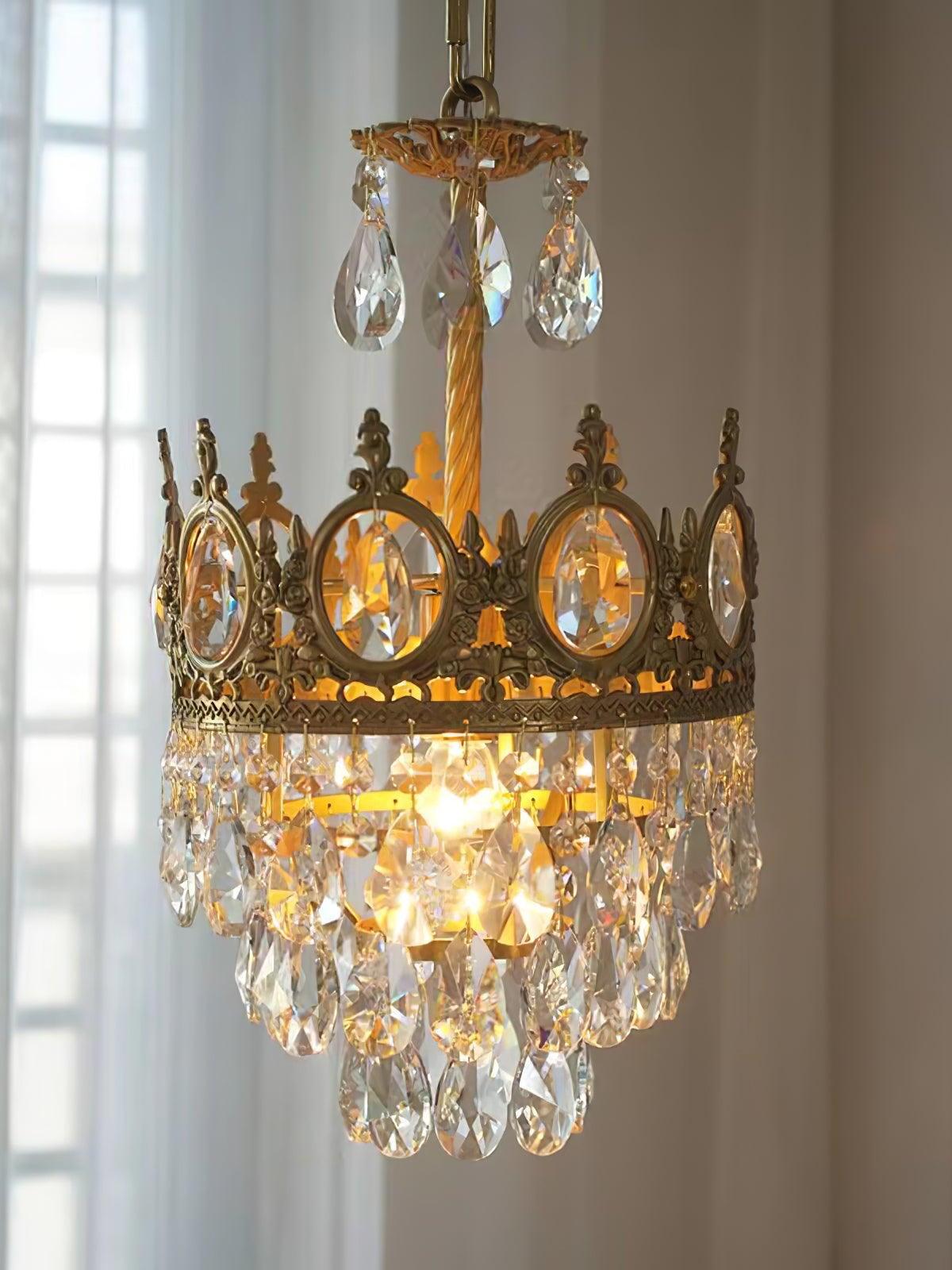 Lit crown-style crystal chandelier beside a window, with clear drops hanging below an upper disc