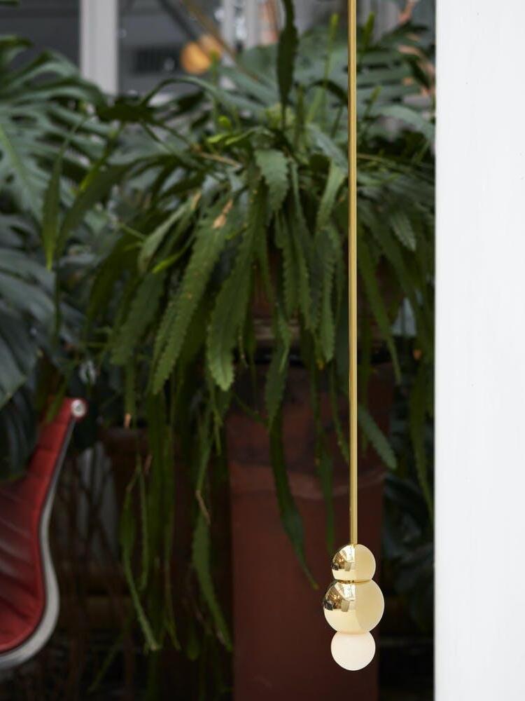 Gold hanging ball light among indoor foliage