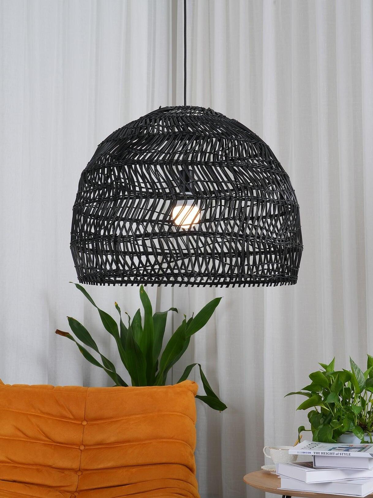 Black wicker pendant above an orange cushion and leafy plants