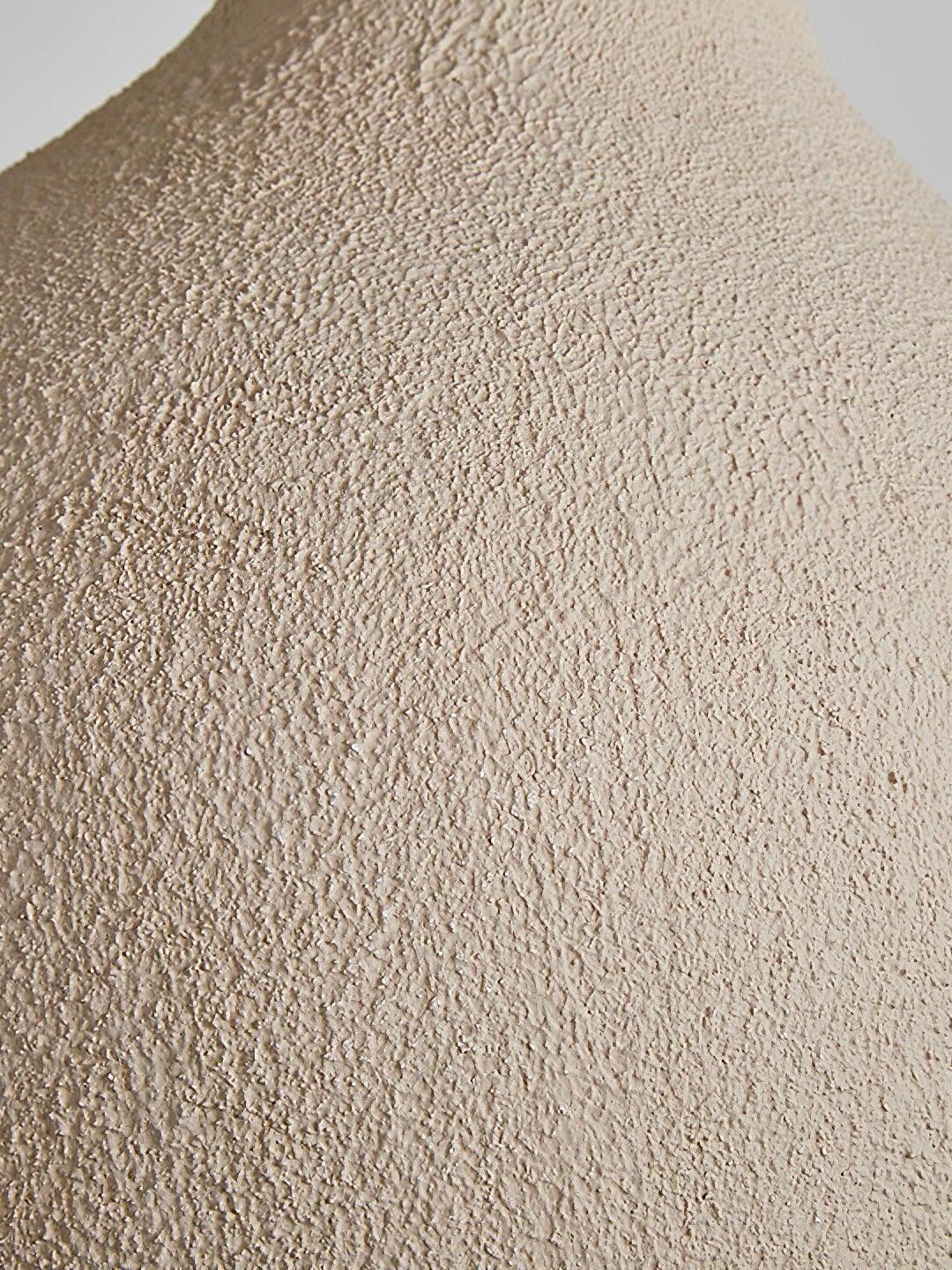 Close-up of the pendant shade’s grainy pale surface with small ridges and pits