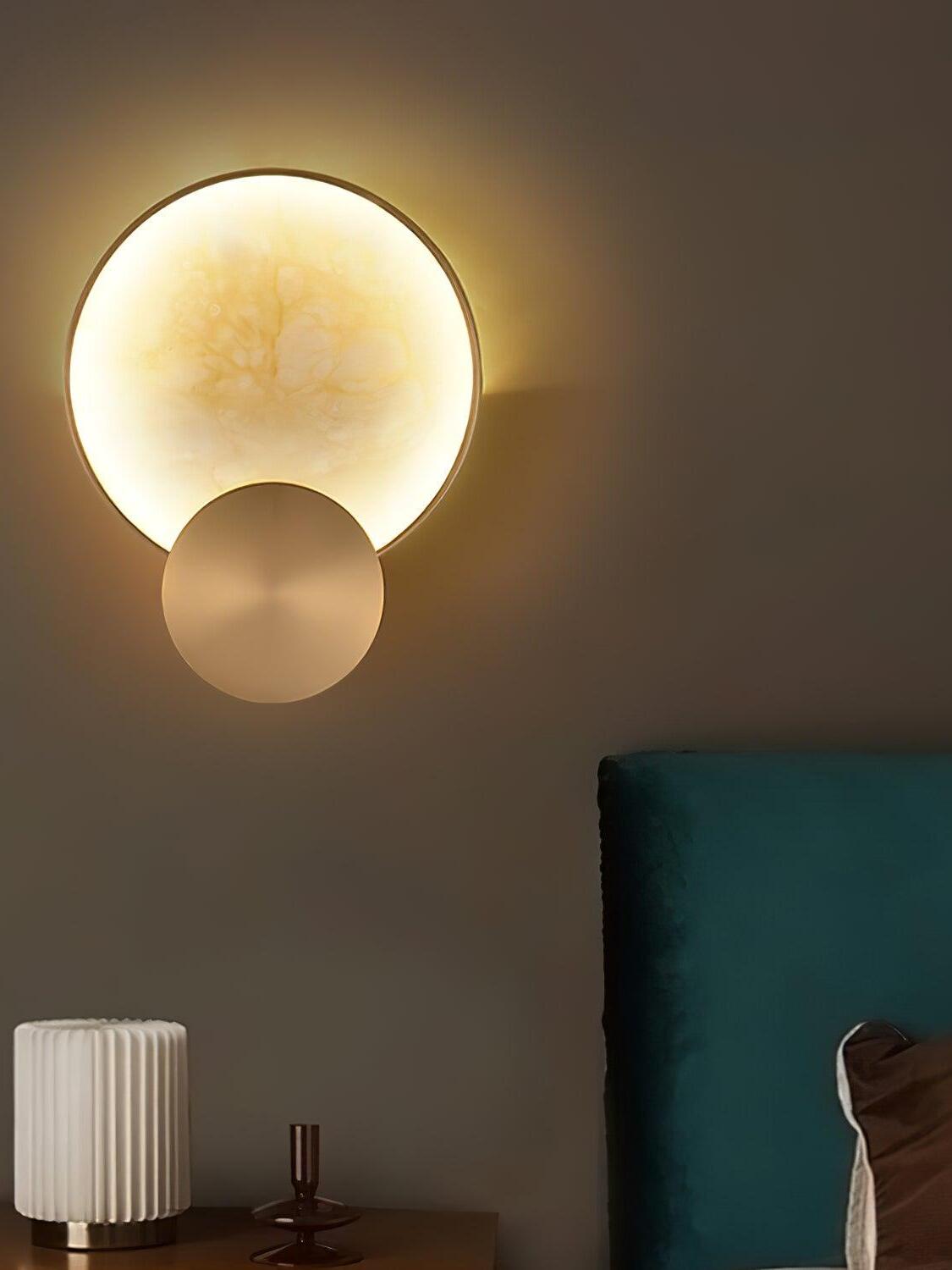 Round alabaster light against a dark wall near furniture