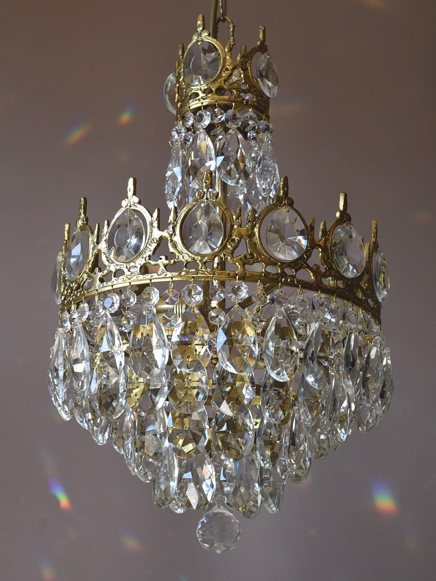 Angled view of a crystal chandelier with a small upper crown and rounded lower cluster of clear drops