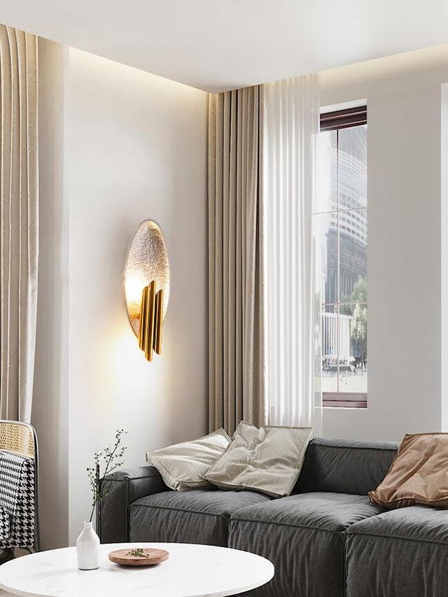 Silver-tone oval wall light above sofa near window and curtains
