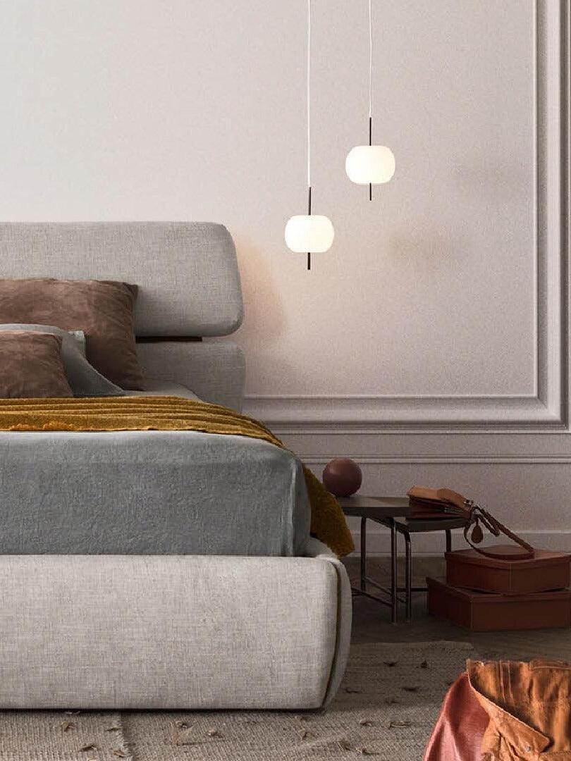 Two small white pendants beside an upholstered bed