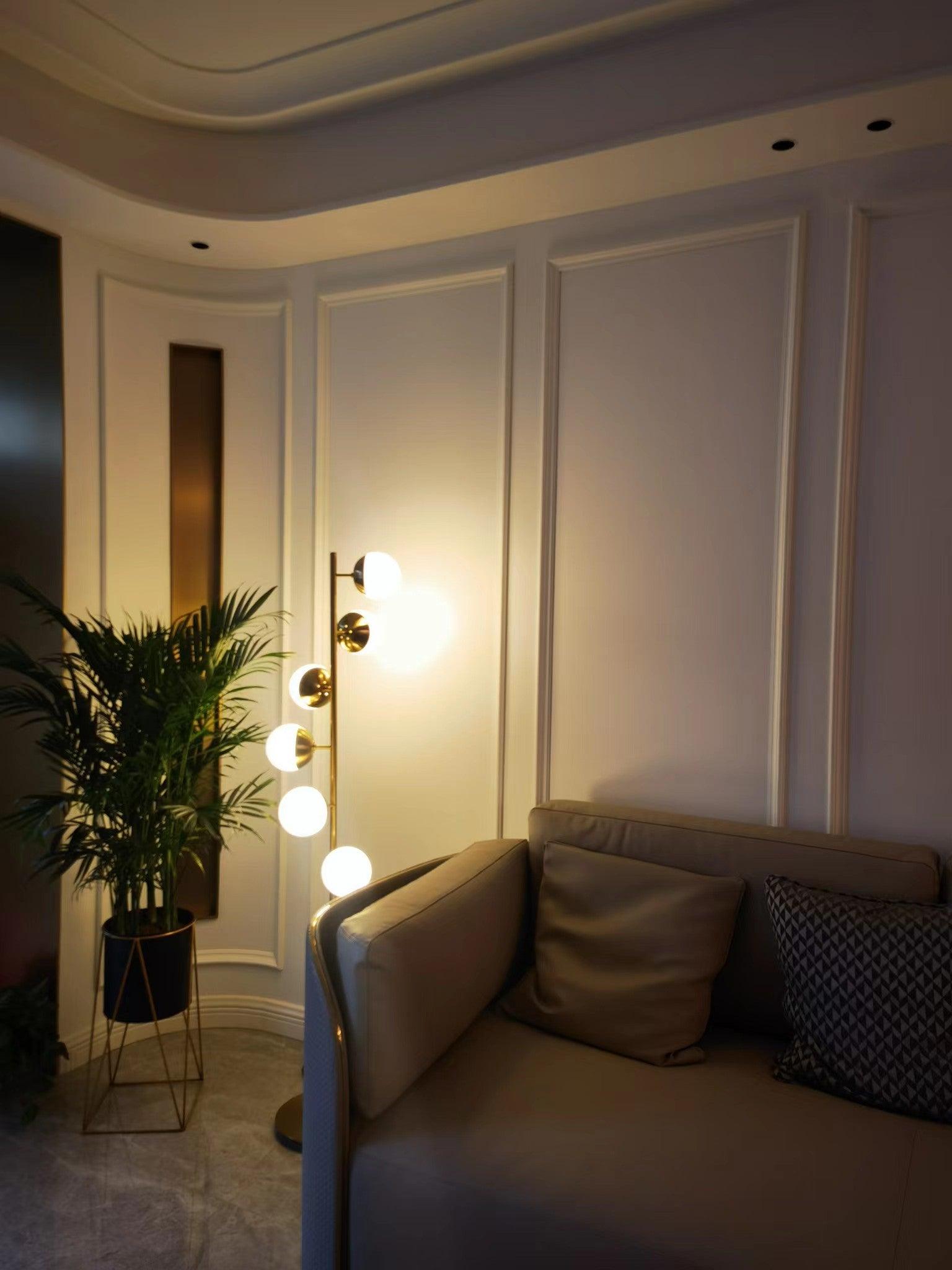 Gold globe floor lamp glowing beside sofa