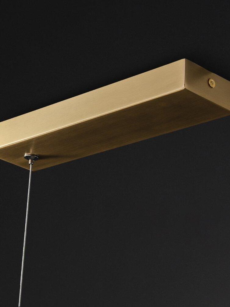Colt rectangular brass-colour canopy close-up, with an end fastener and a suspension wire against black