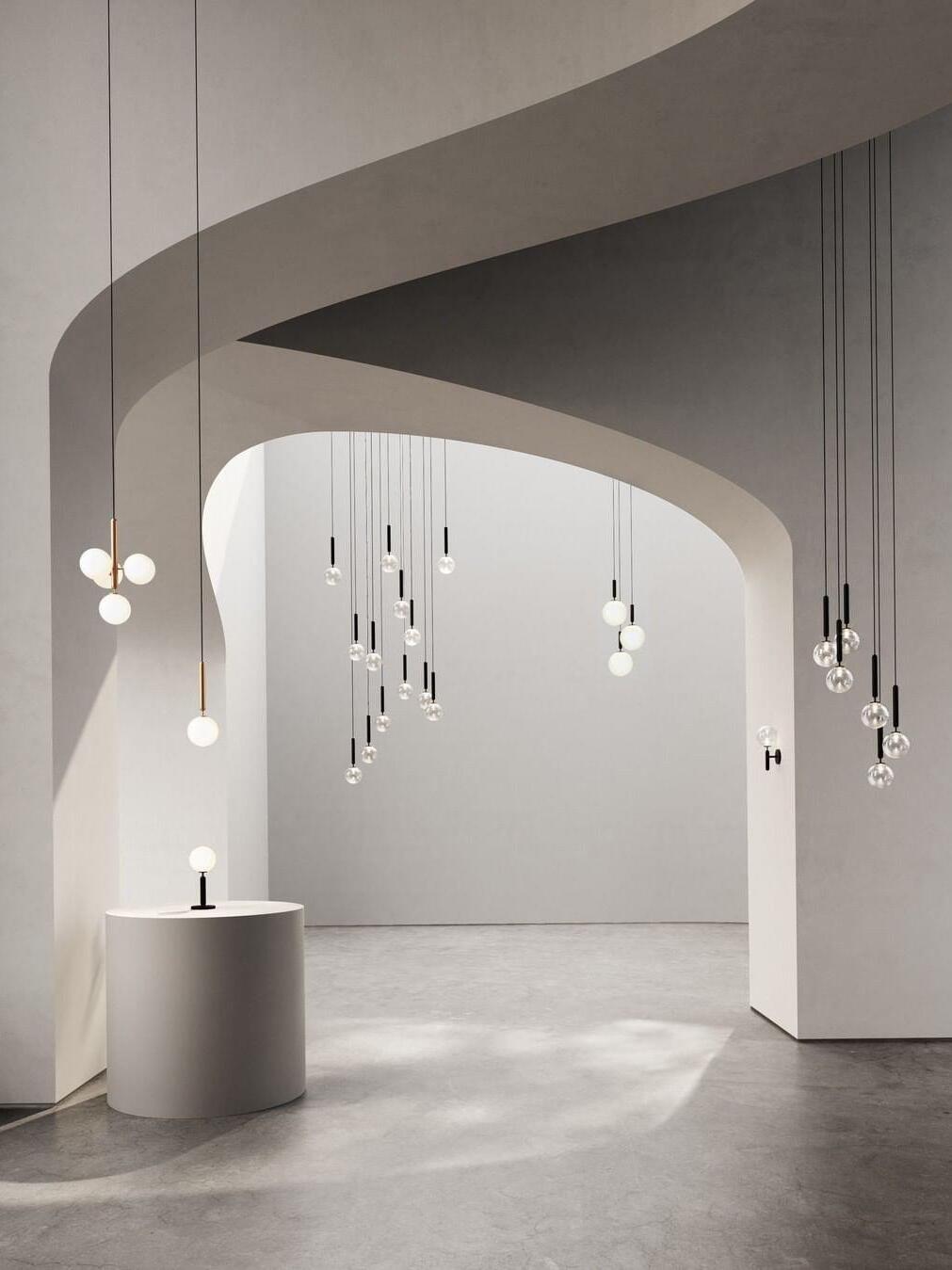 Assorted globe pendants and separate wall and table lights displayed beneath curved showroom arches