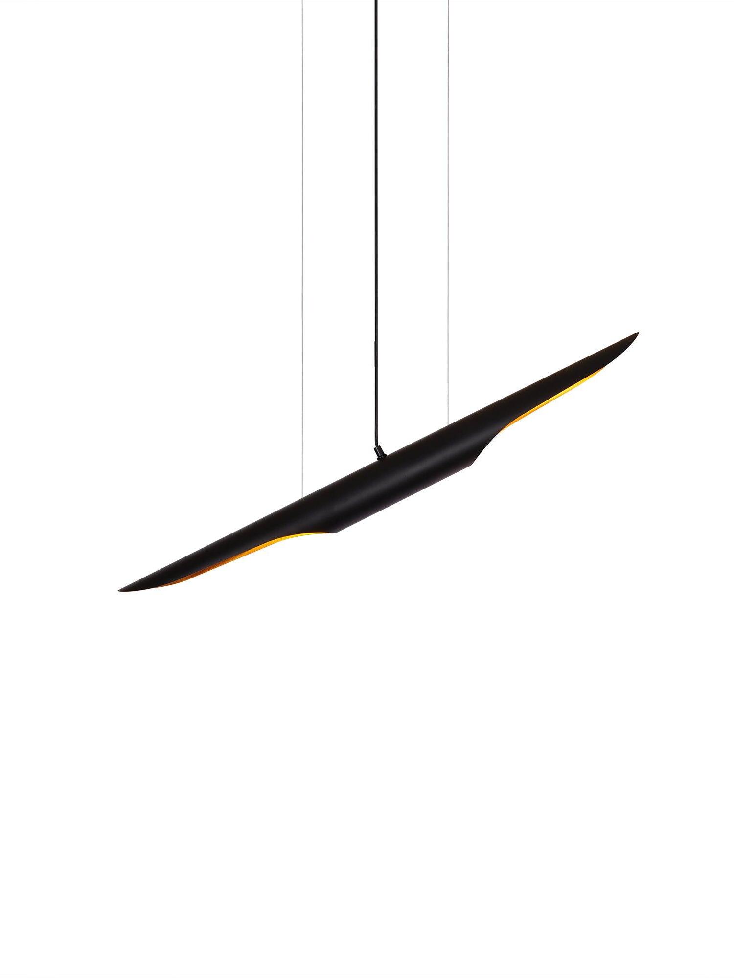 Single suspended black pipe pendant with gold-tone diagonal end openings against a white background