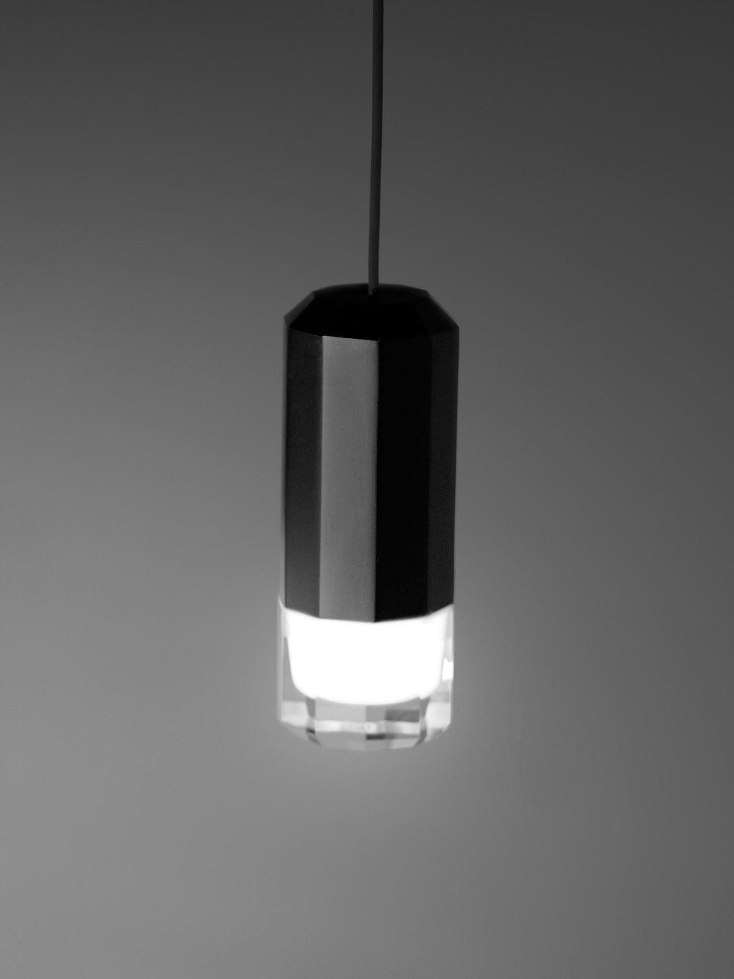 Close-up of a faceted black pendant head with illuminated pale and clear lower sections