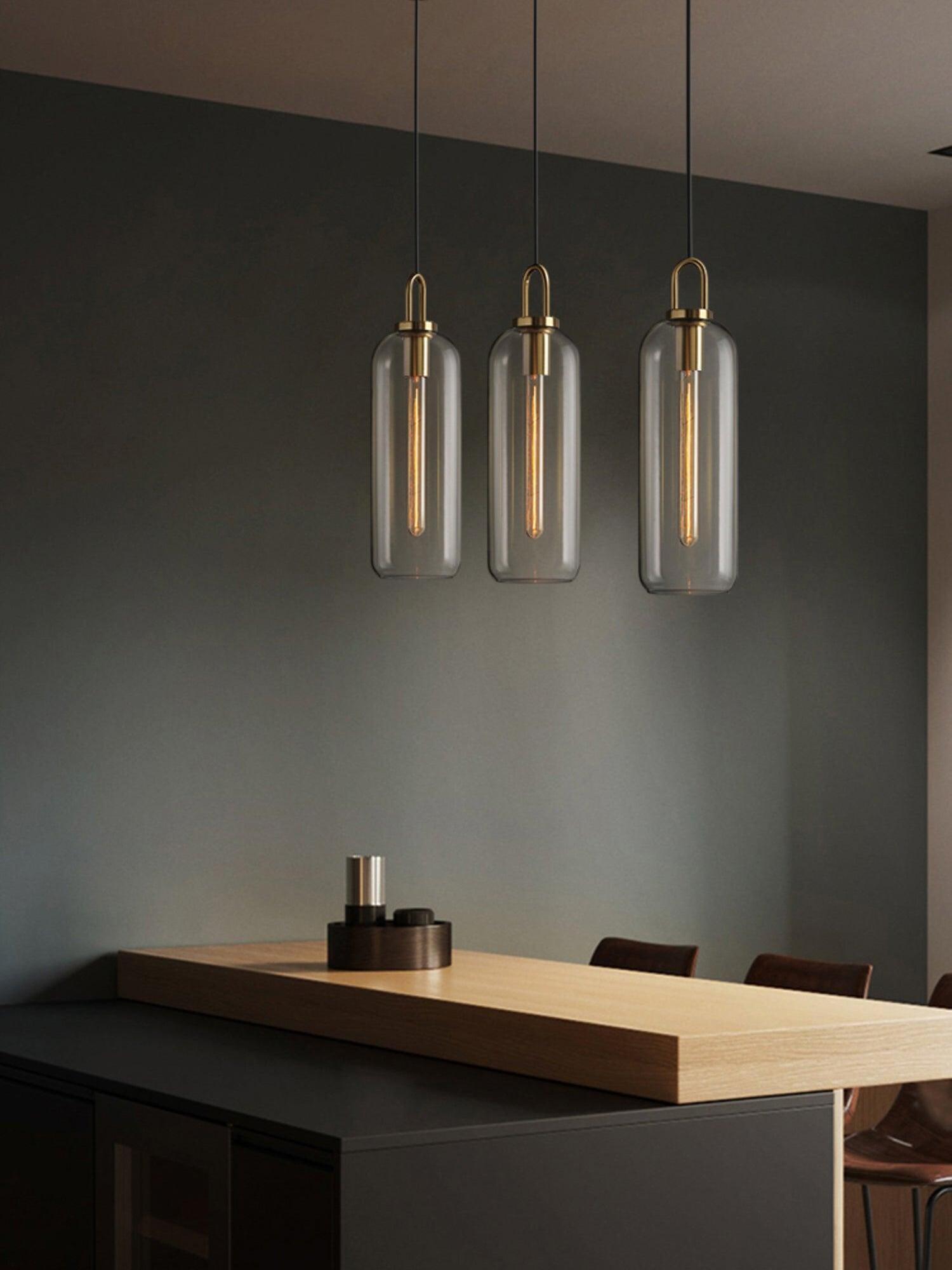 Three clear capsule pendants above a kitchen counter