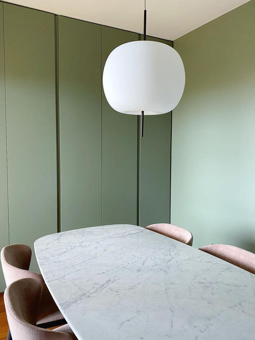 White glass pendant with black stem over a pale table