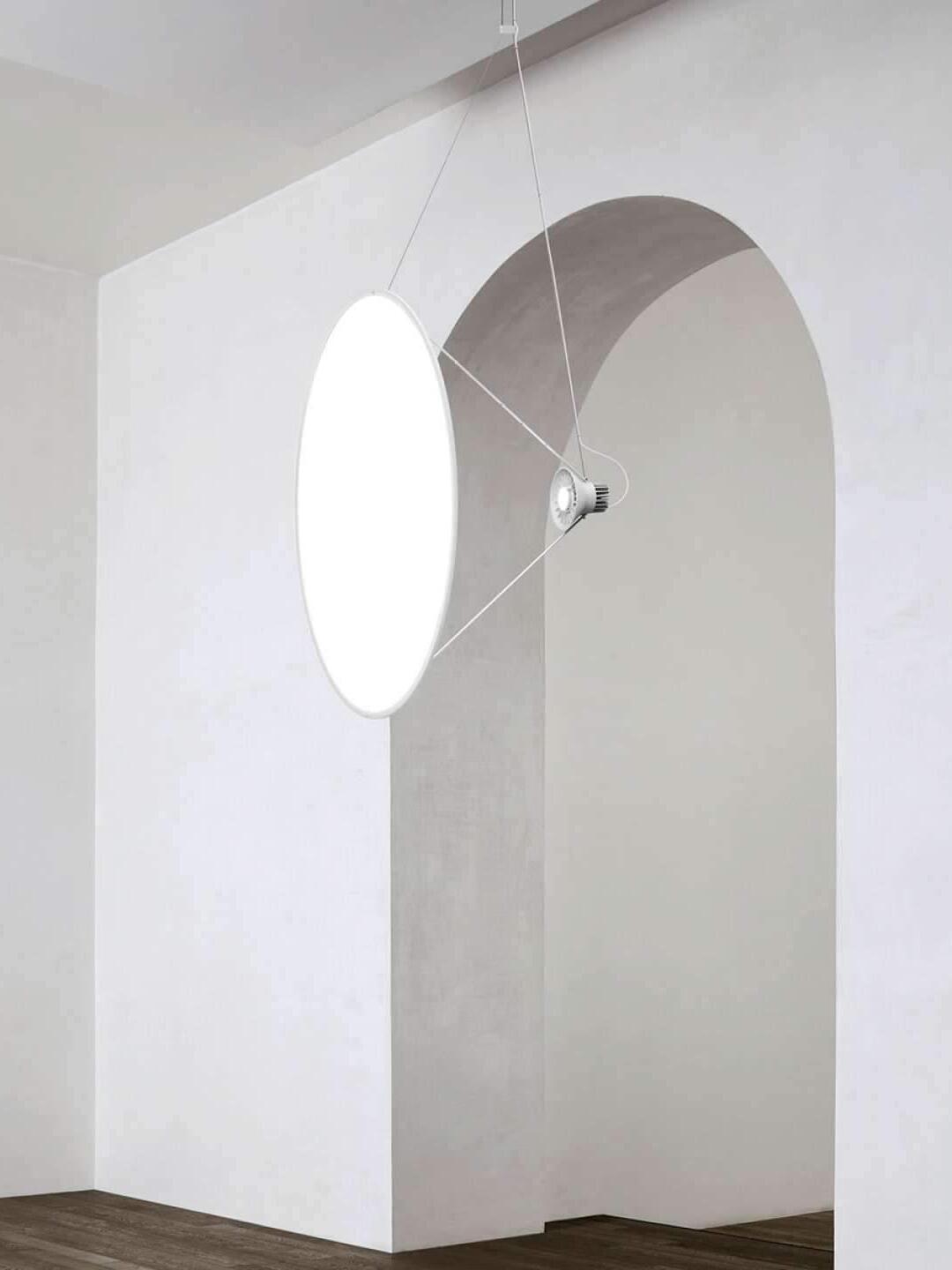 Large pale reflector disc beside an interior wall