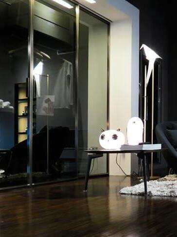 Small owl and penguin on round table near glass cabinets and floor light