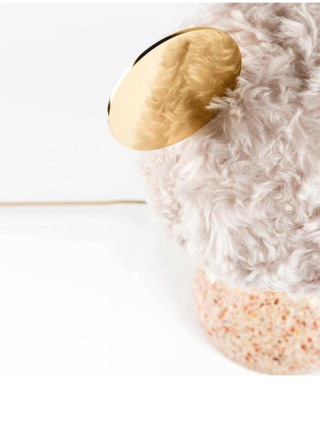 Angled close view of pale plush shade, circular disc and speckled base