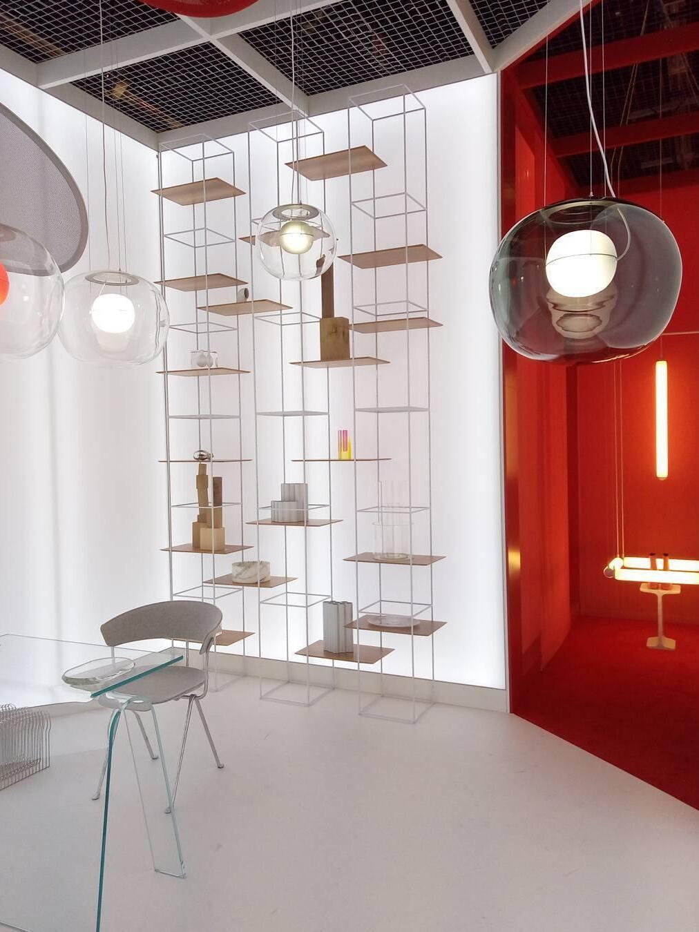 Glass pendant group beside a red wall and tall shelving