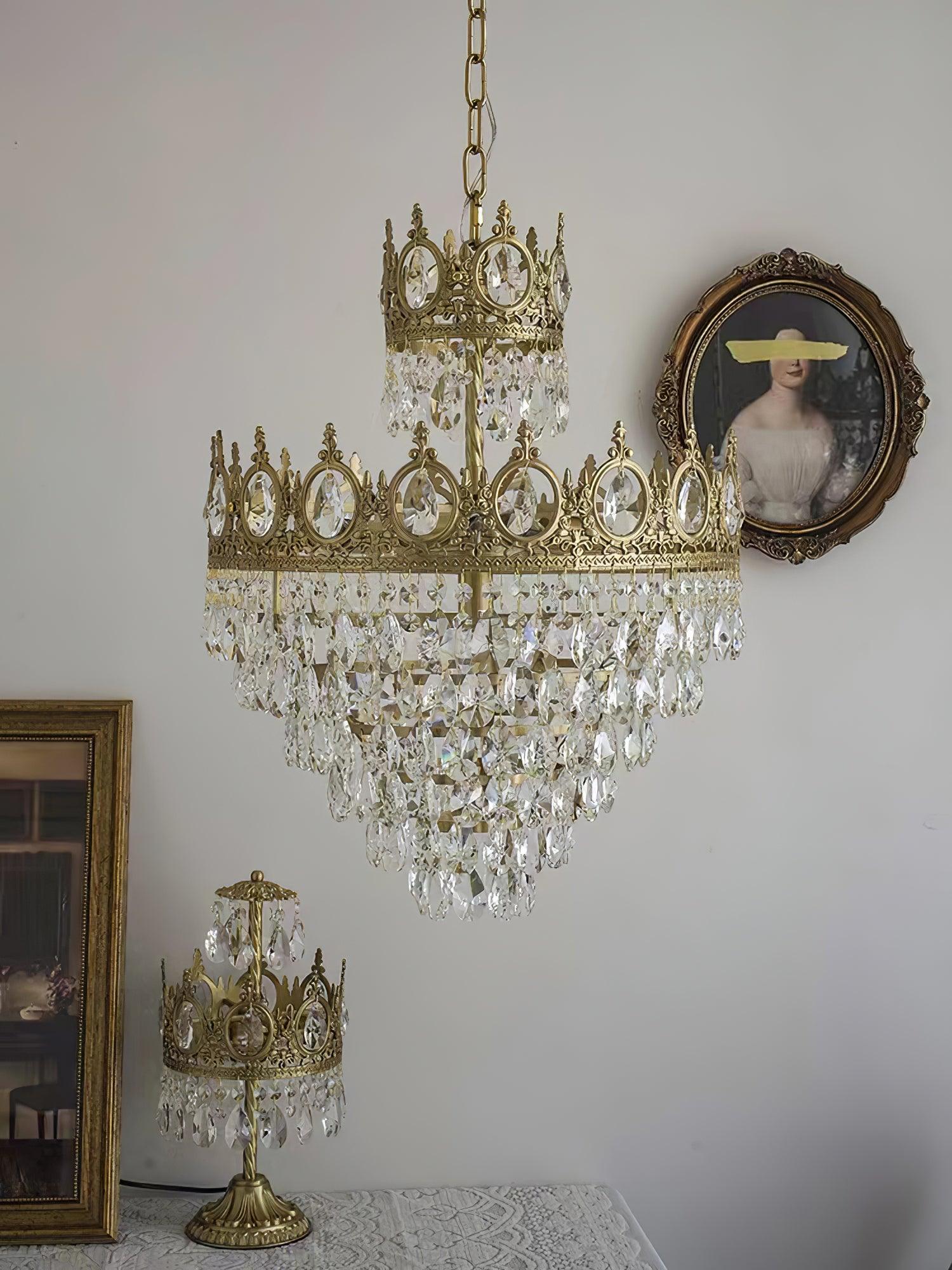 Crystal chandelier in a white room with framed artwork and a separate ornate table lamp below
