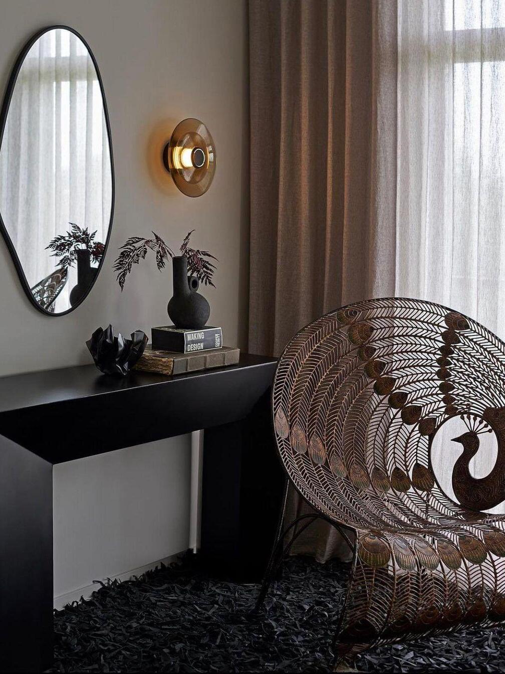 Gold amber wall light beside round mirror and console