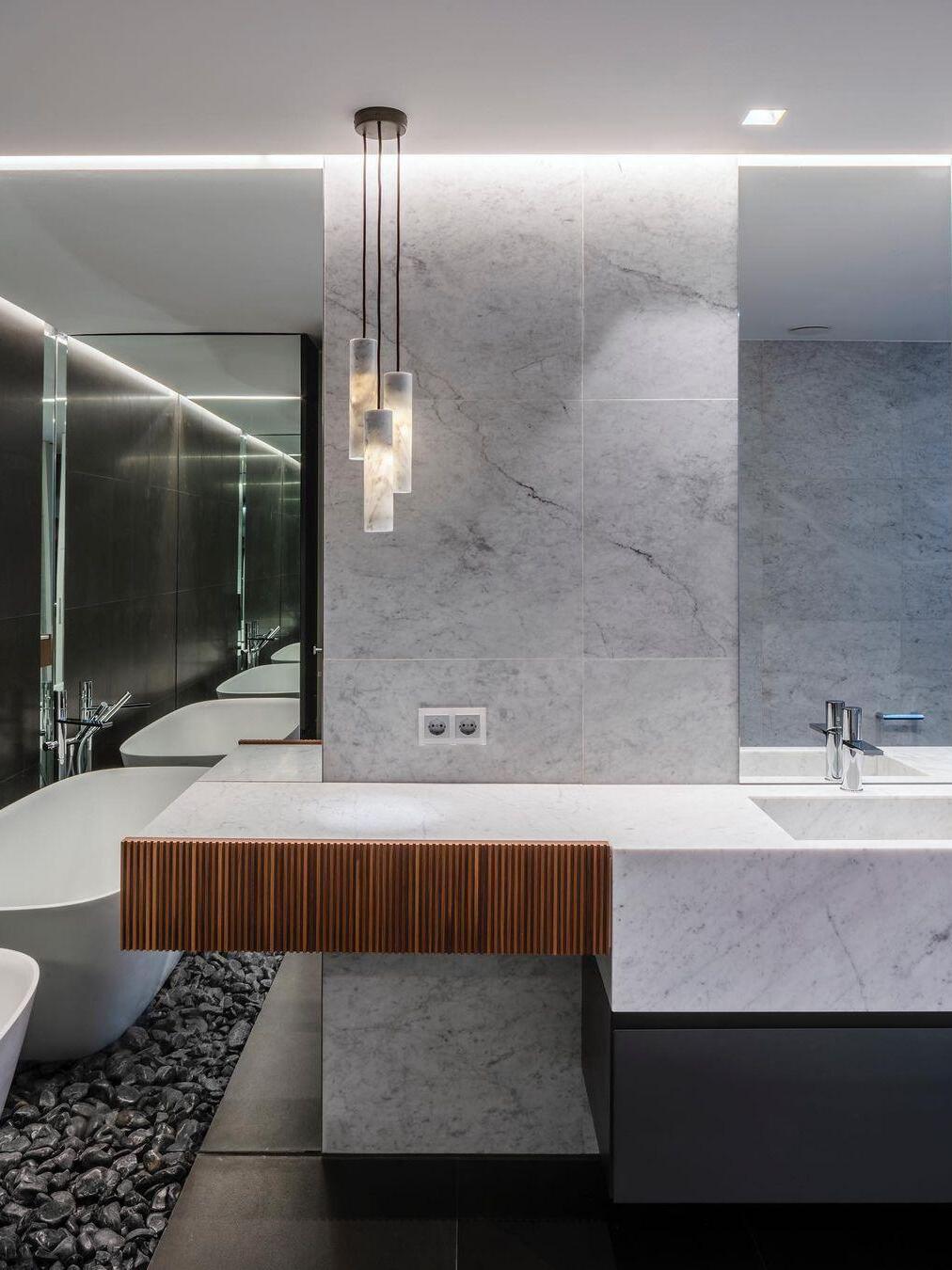 Three glowing Silo cylinders beside a bathroom mirror above a pale stone basin and counter