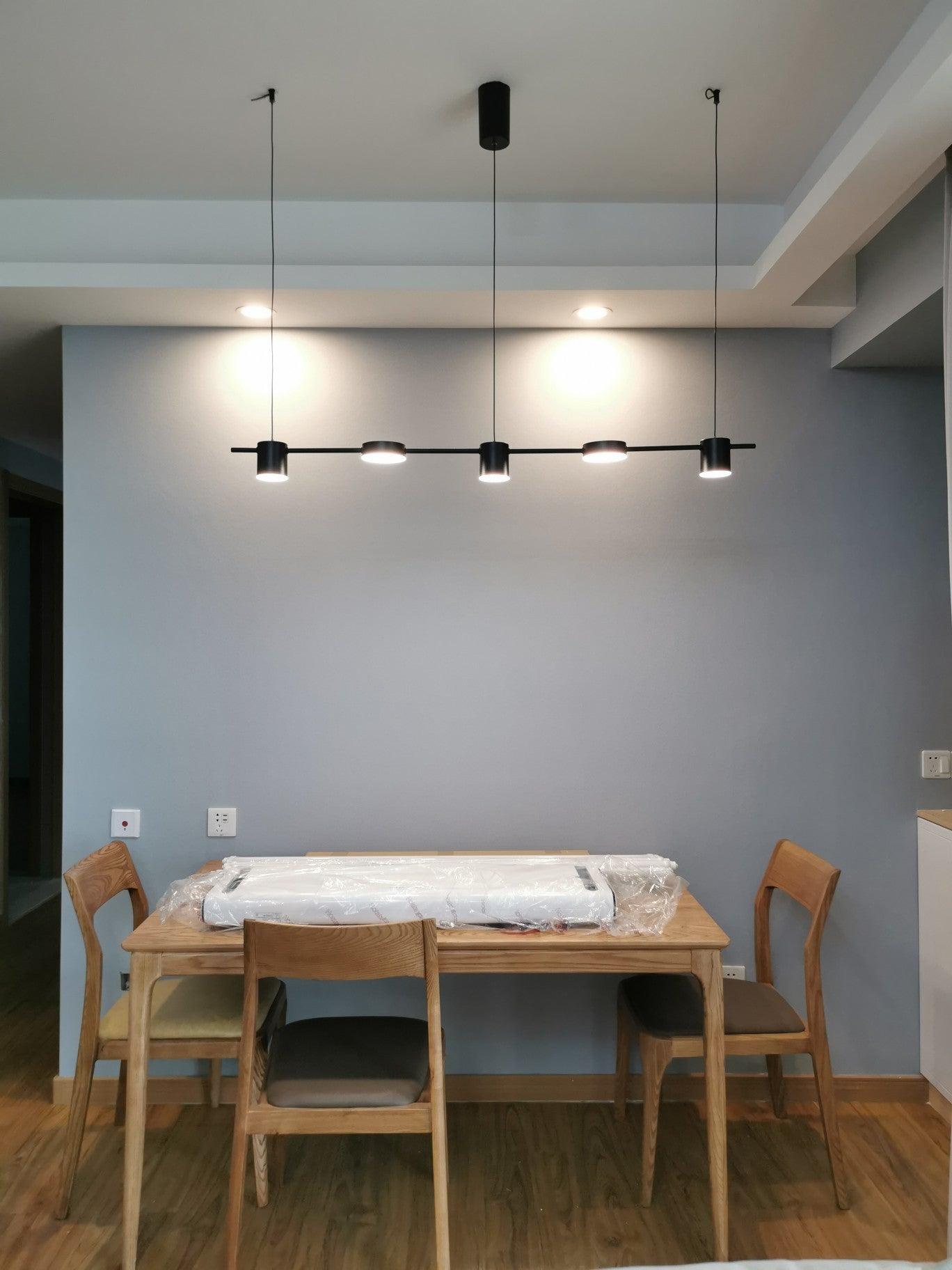 Black linear light illuminating a dining area