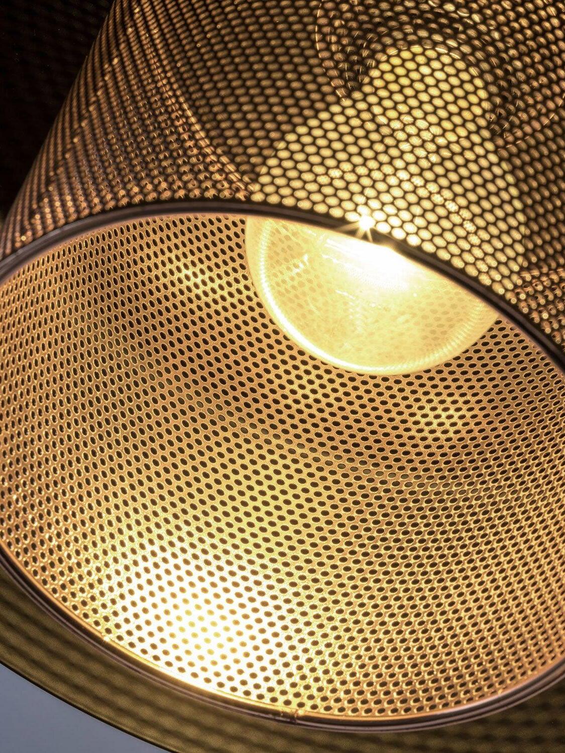 Close underside of the perforated copper-tone shade with a glowing bulb visible through the holes