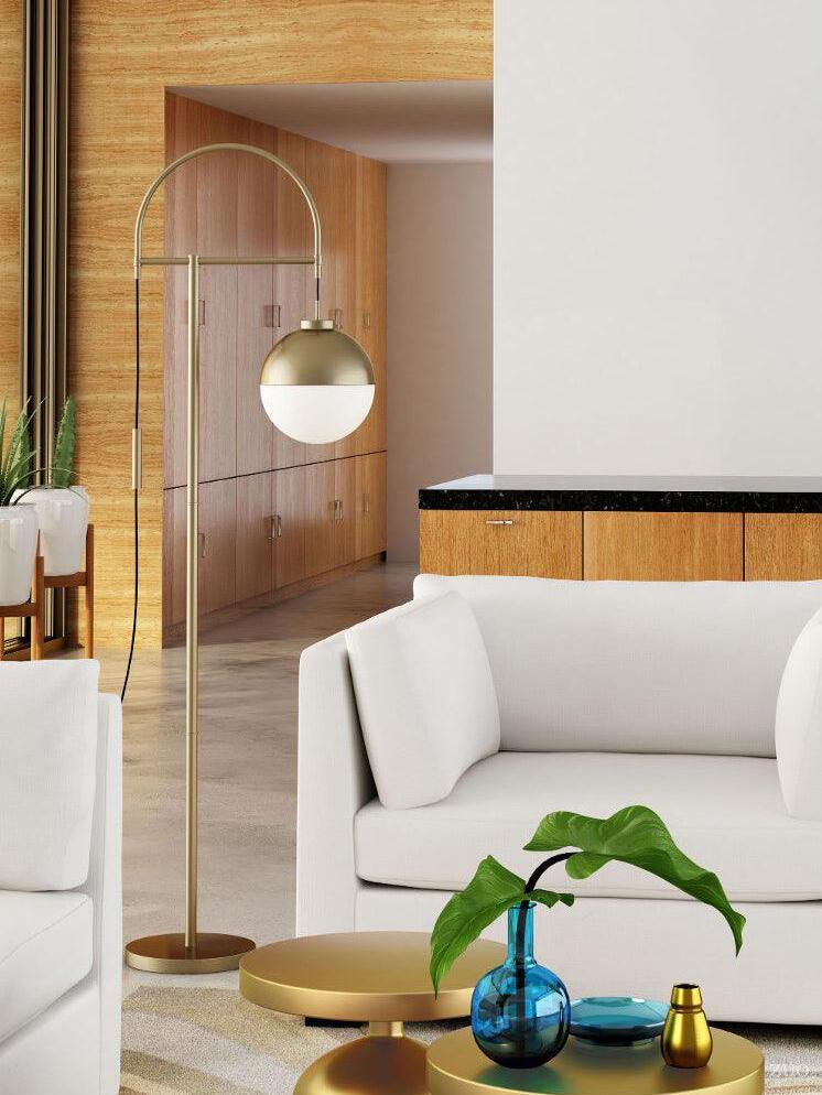 Waterloo Gold arc floor lamp beside a white sofa